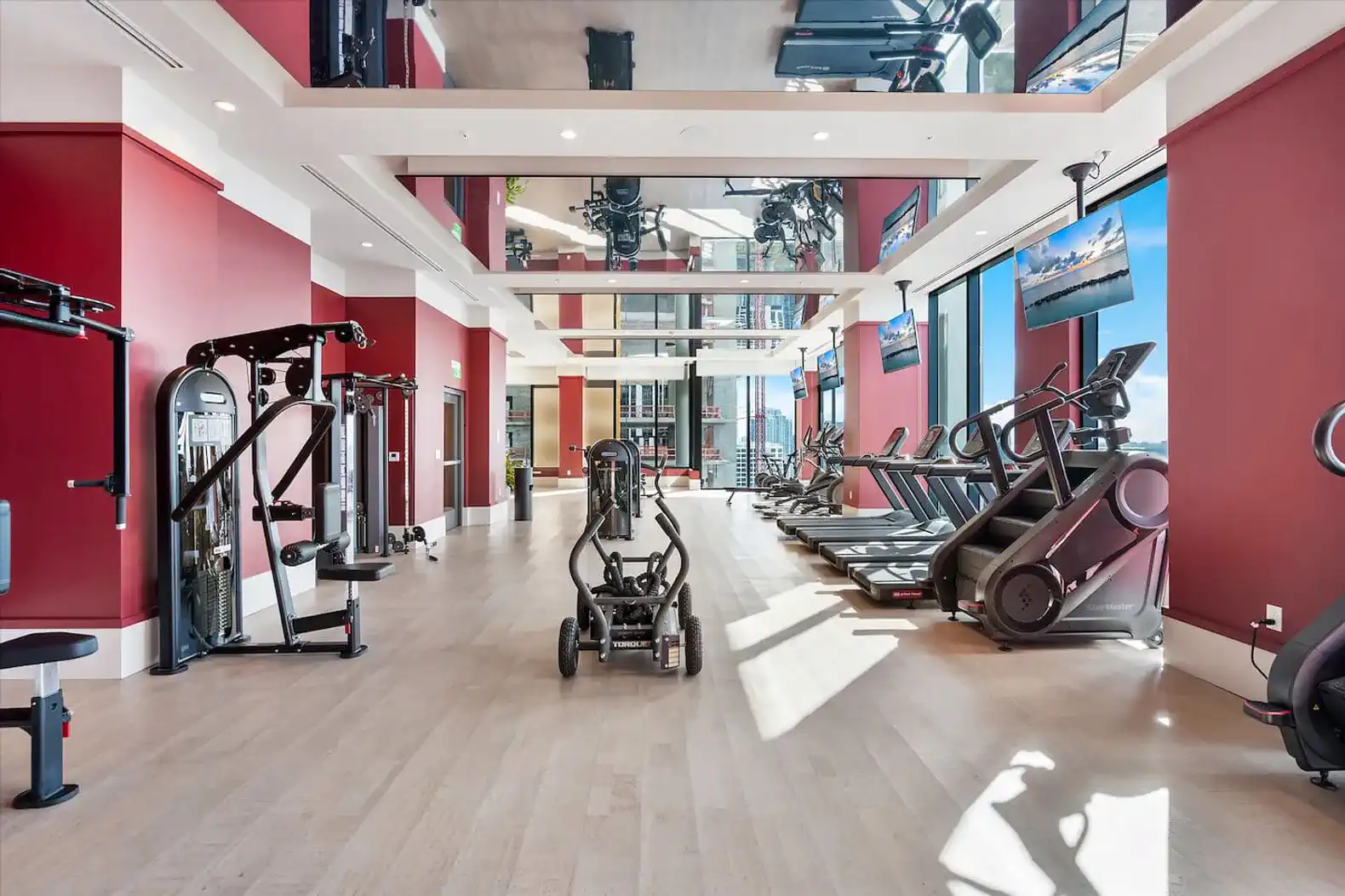 spacious modern gym with various exercise equipment and large windows
