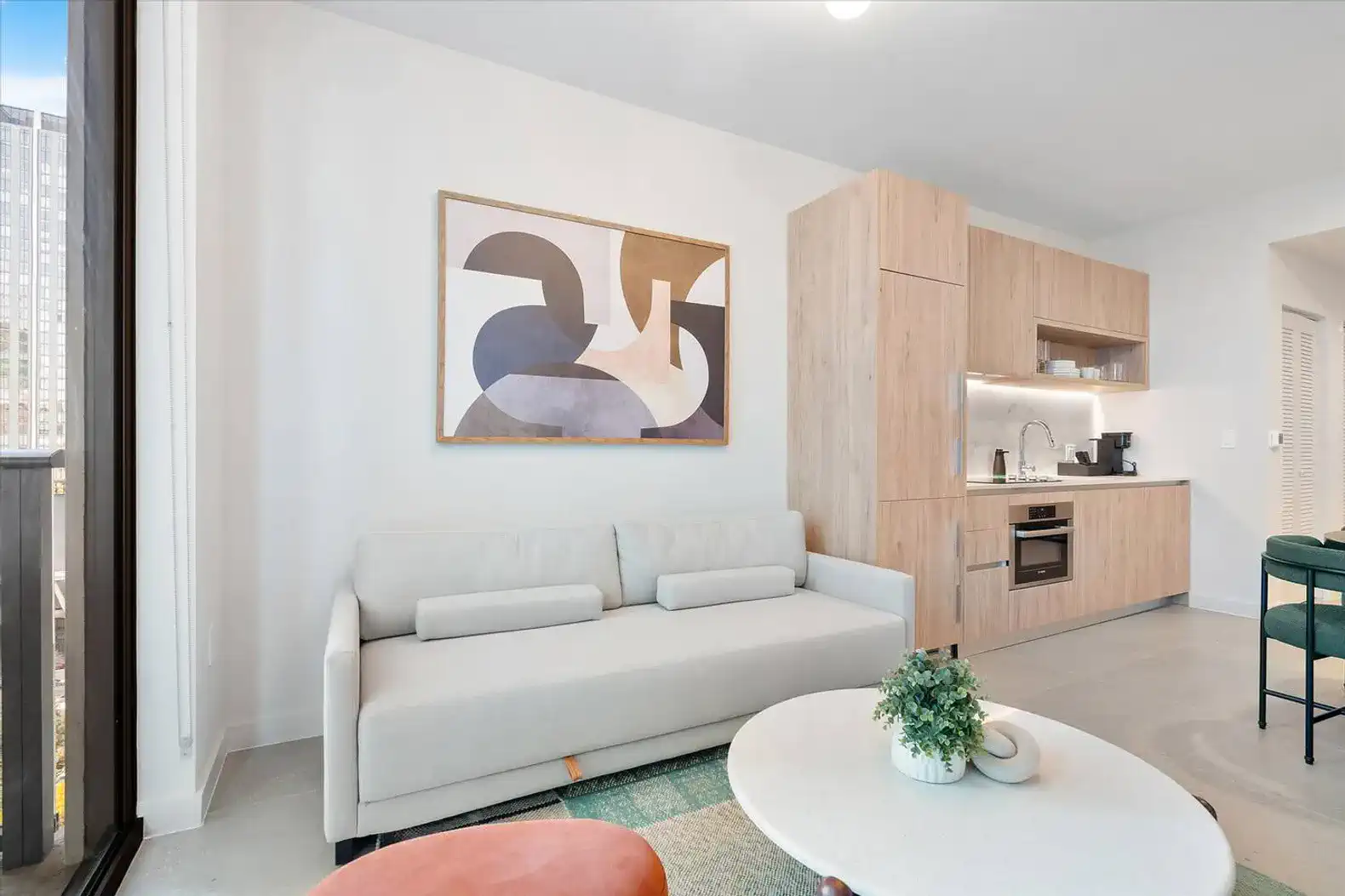Modern living area with a sofa, kitchenette, and abstract wall art