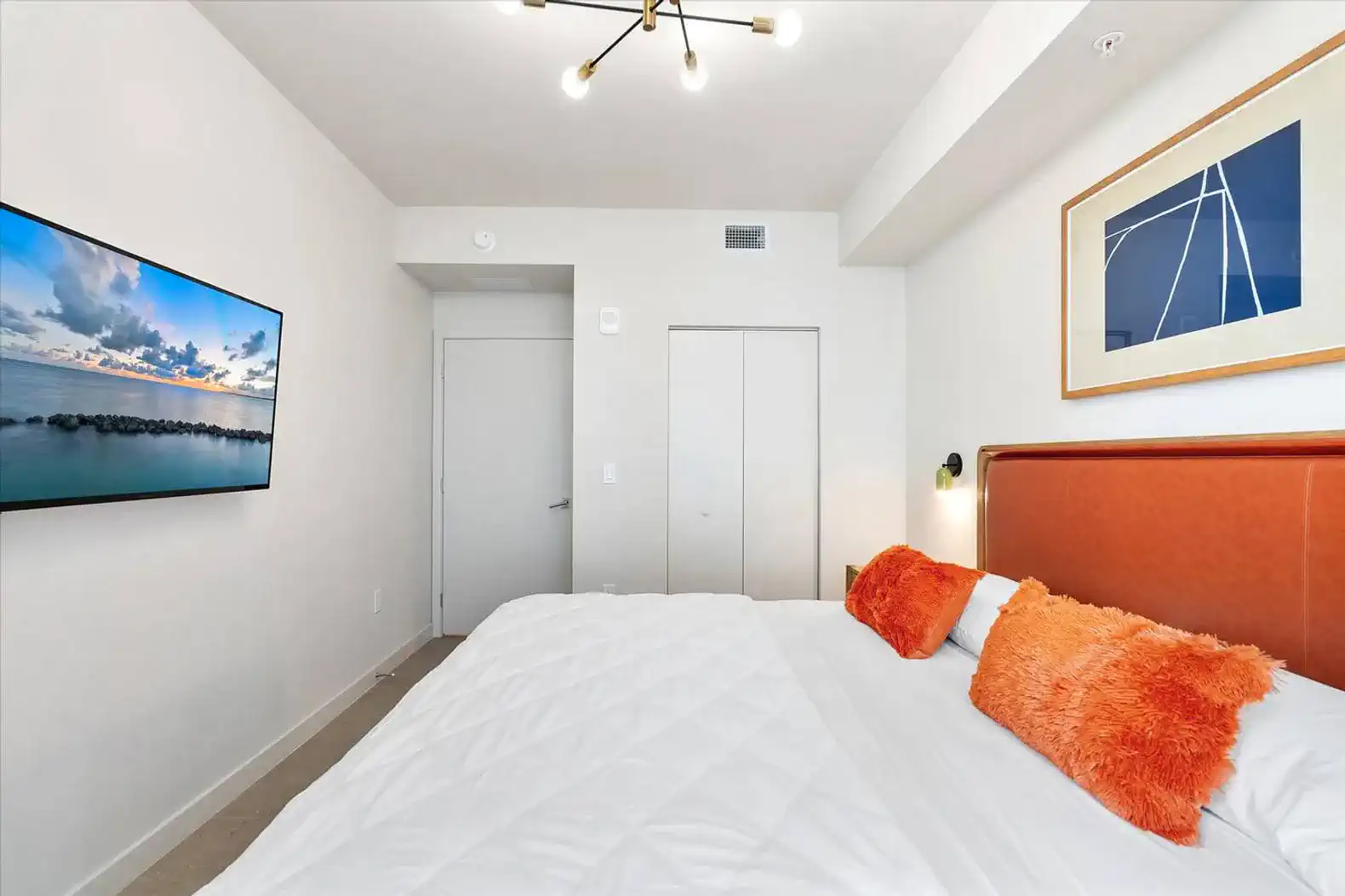 Cozy master bedroom with a large bed, decorative pillows, and a wall-mounted TV