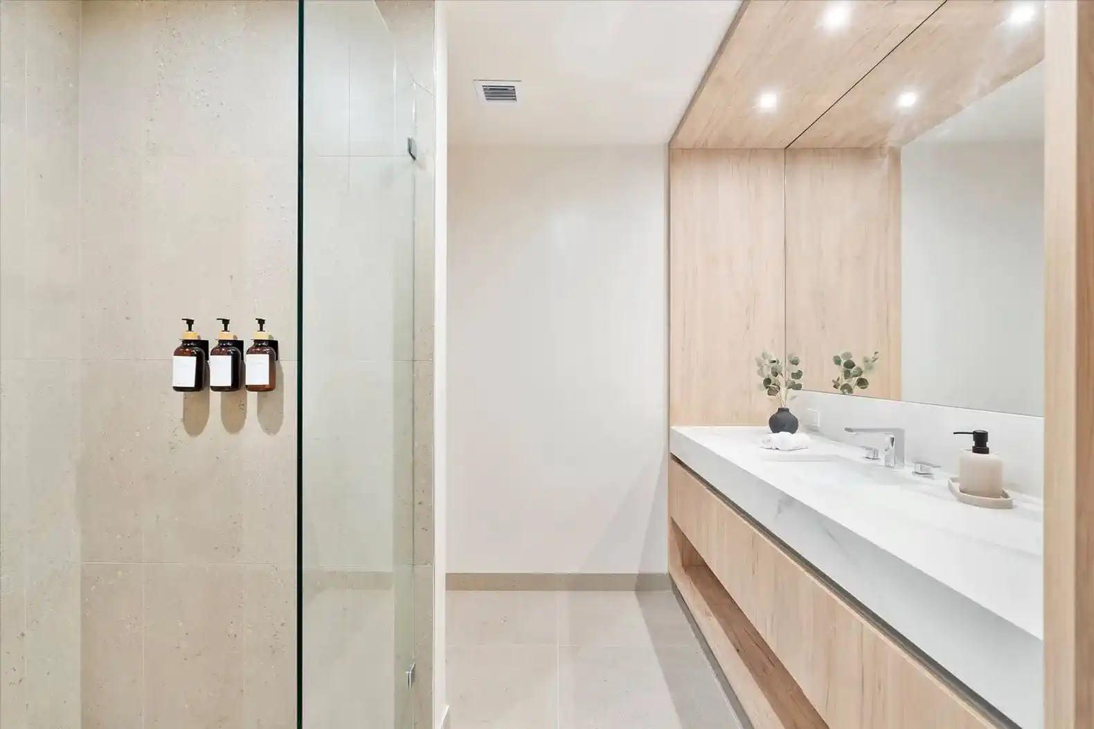 Modern bathroom with glass shower, dual sinks, and wooden cabinetry