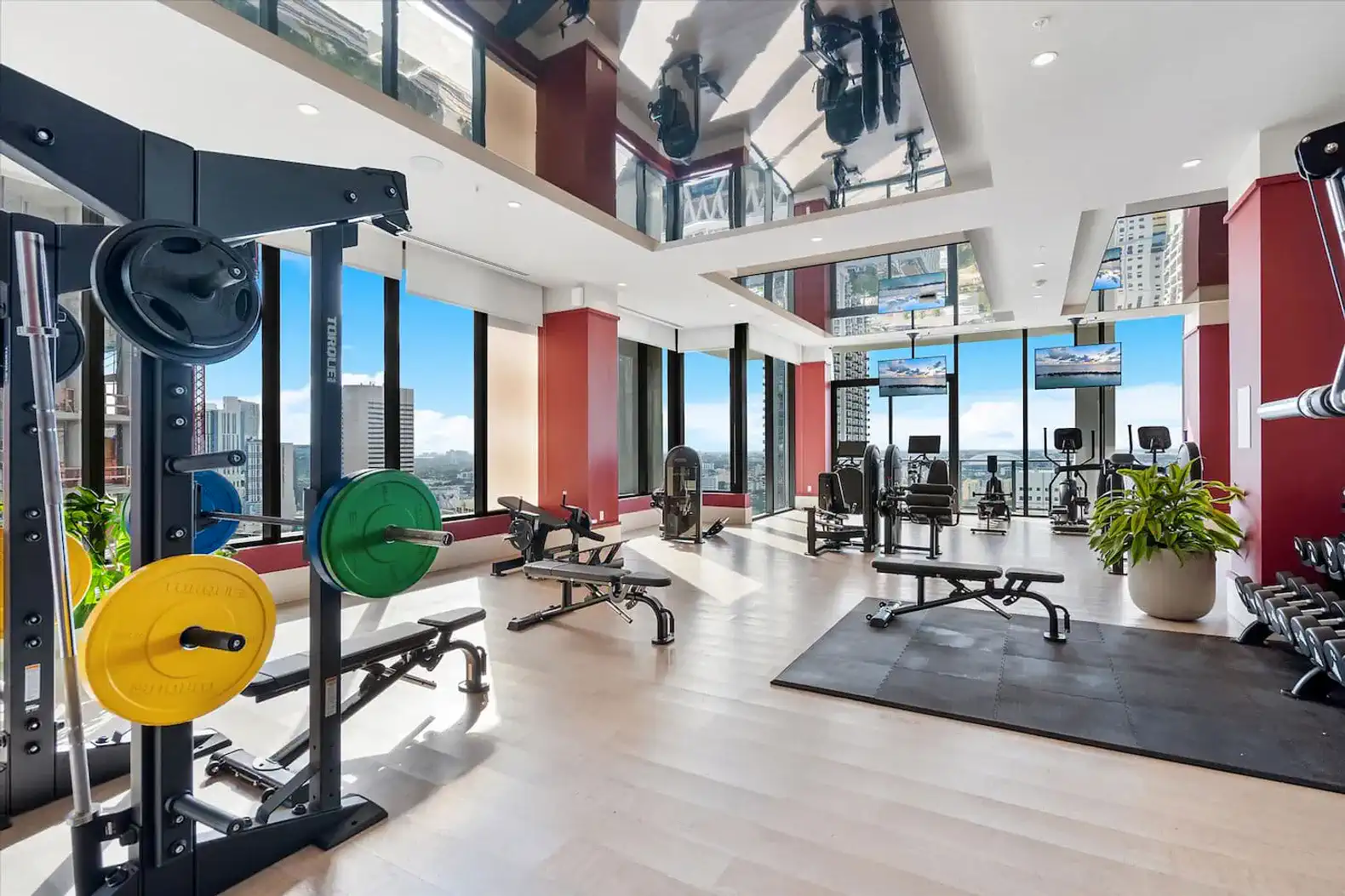 modern gym with weightlifting equipment and large windows showcasing city views