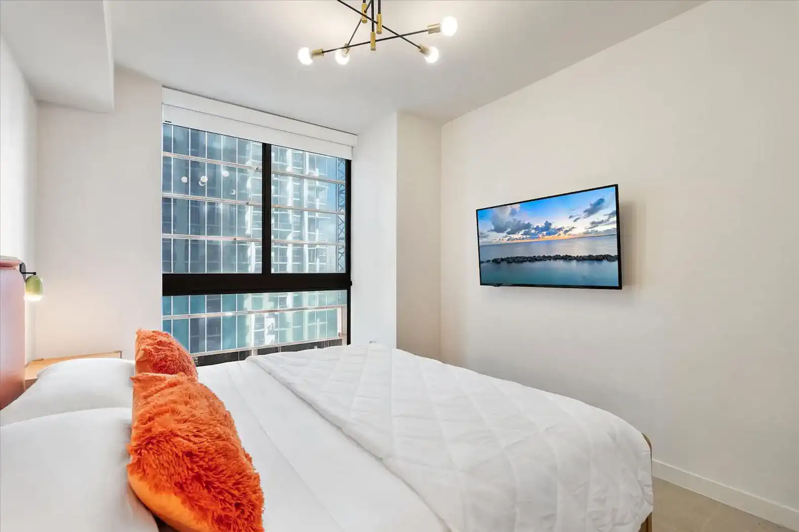 Cozy bedroom with a large window showcasing city views and a mounted TV