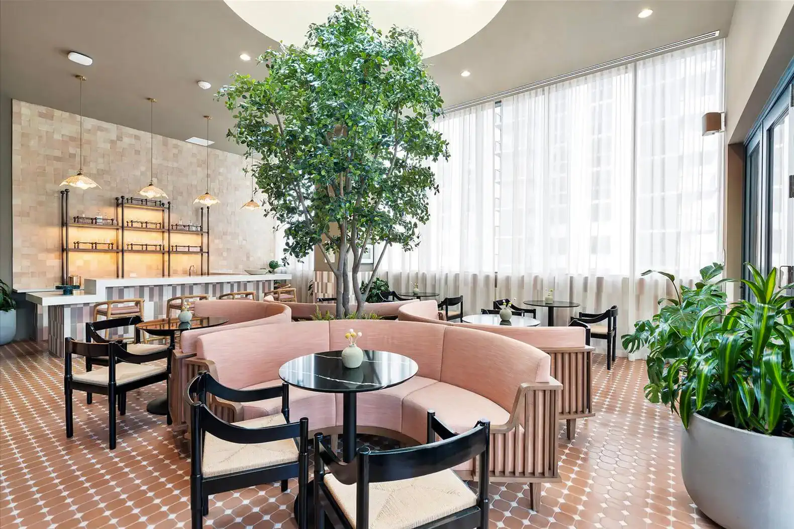 Stylish lounge area with pink seating, greenery, and large windows