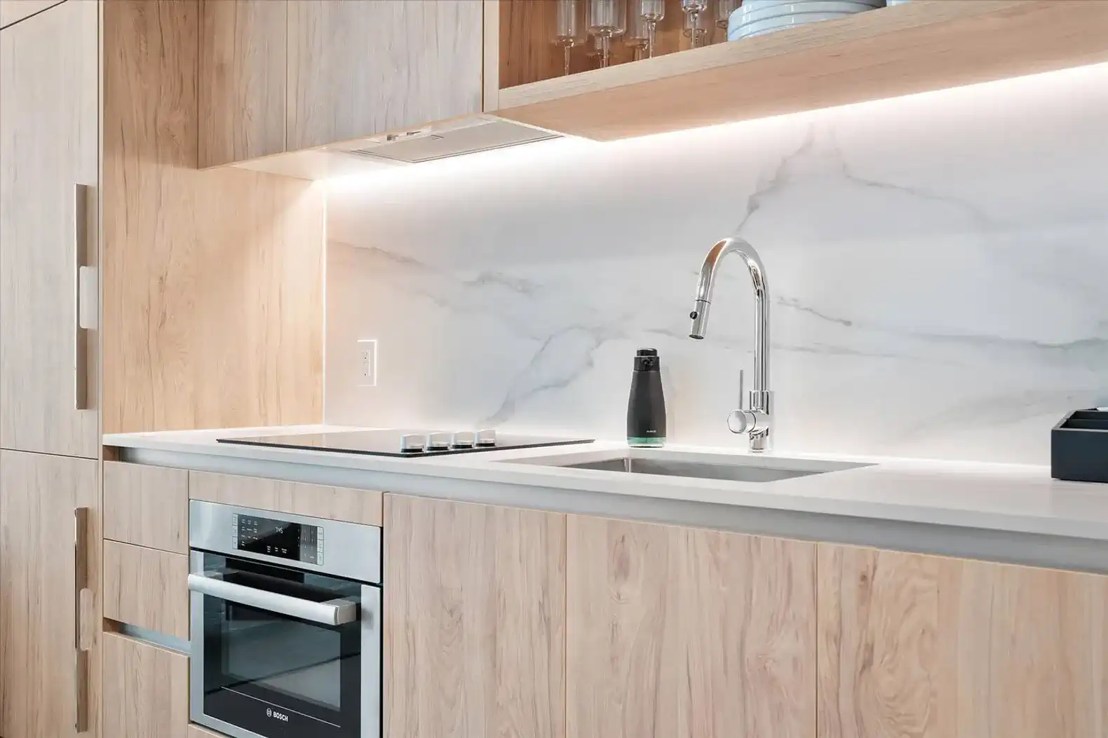 Modern kitchen with sleek cabinetry, marble backsplash, and stainless steel appliances