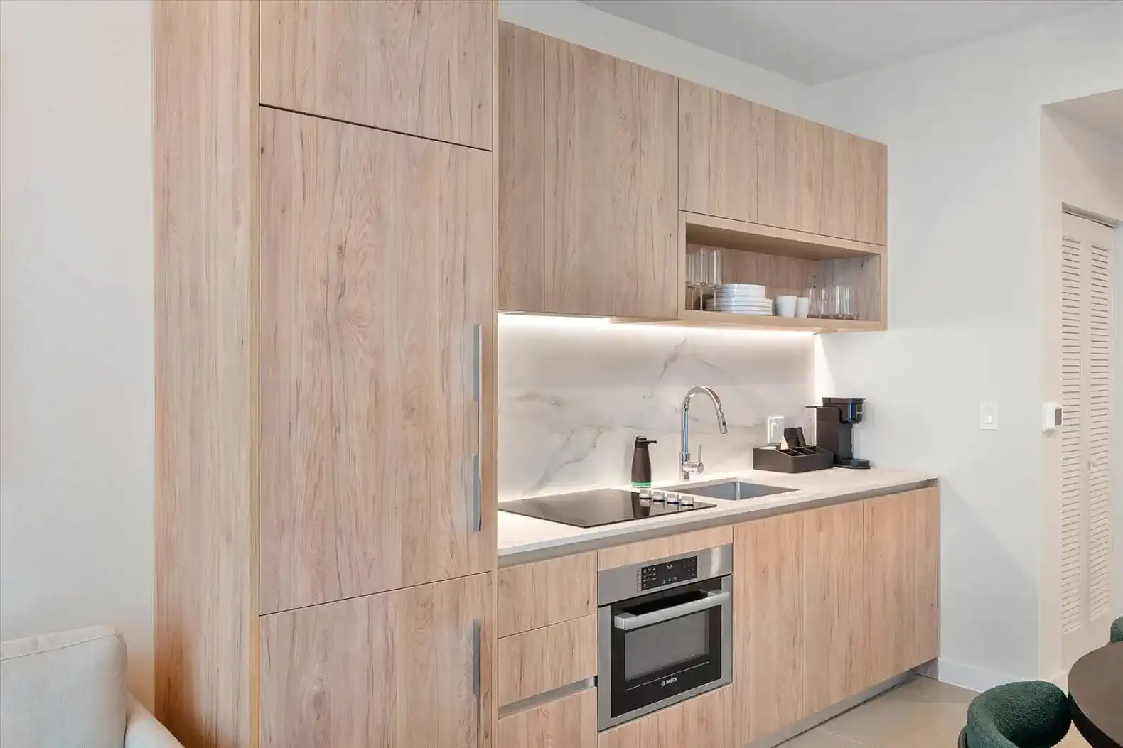Modern kitchen with wooden cabinetry, marble backsplash, and stainless steel appliances