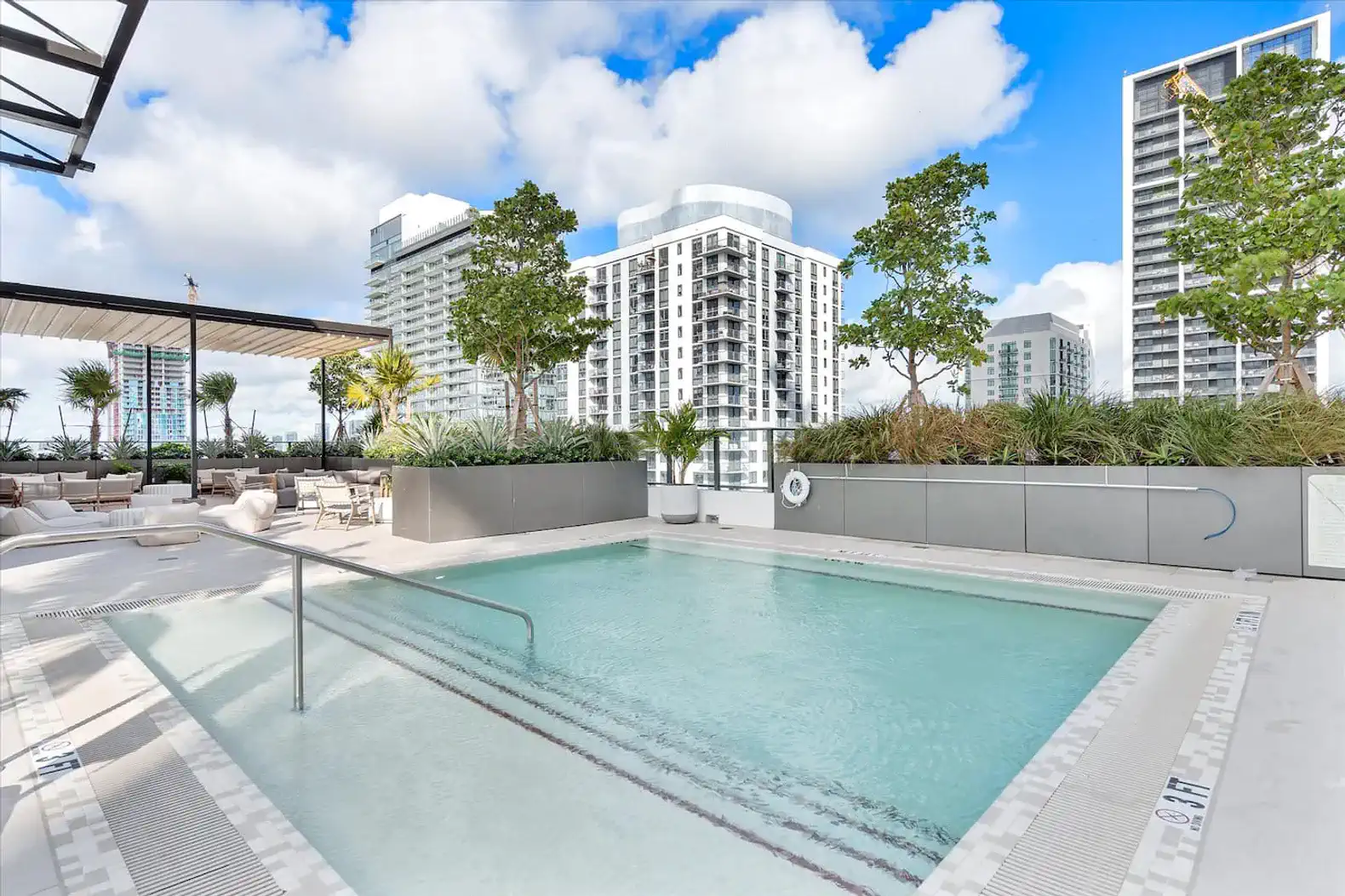 Modern pool area surrounded by greenery and city skyline