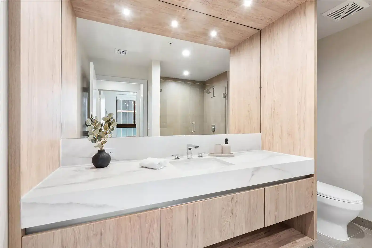 Modern bathroom with wooden cabinetry and large mirror