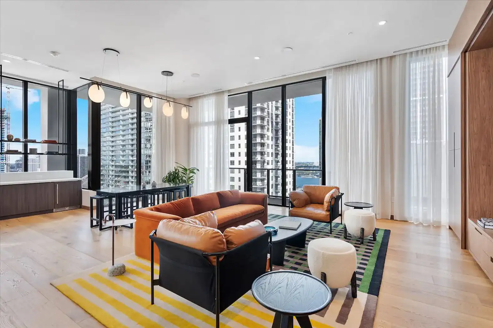 Spacious living room with modern furniture, large windows, and city views