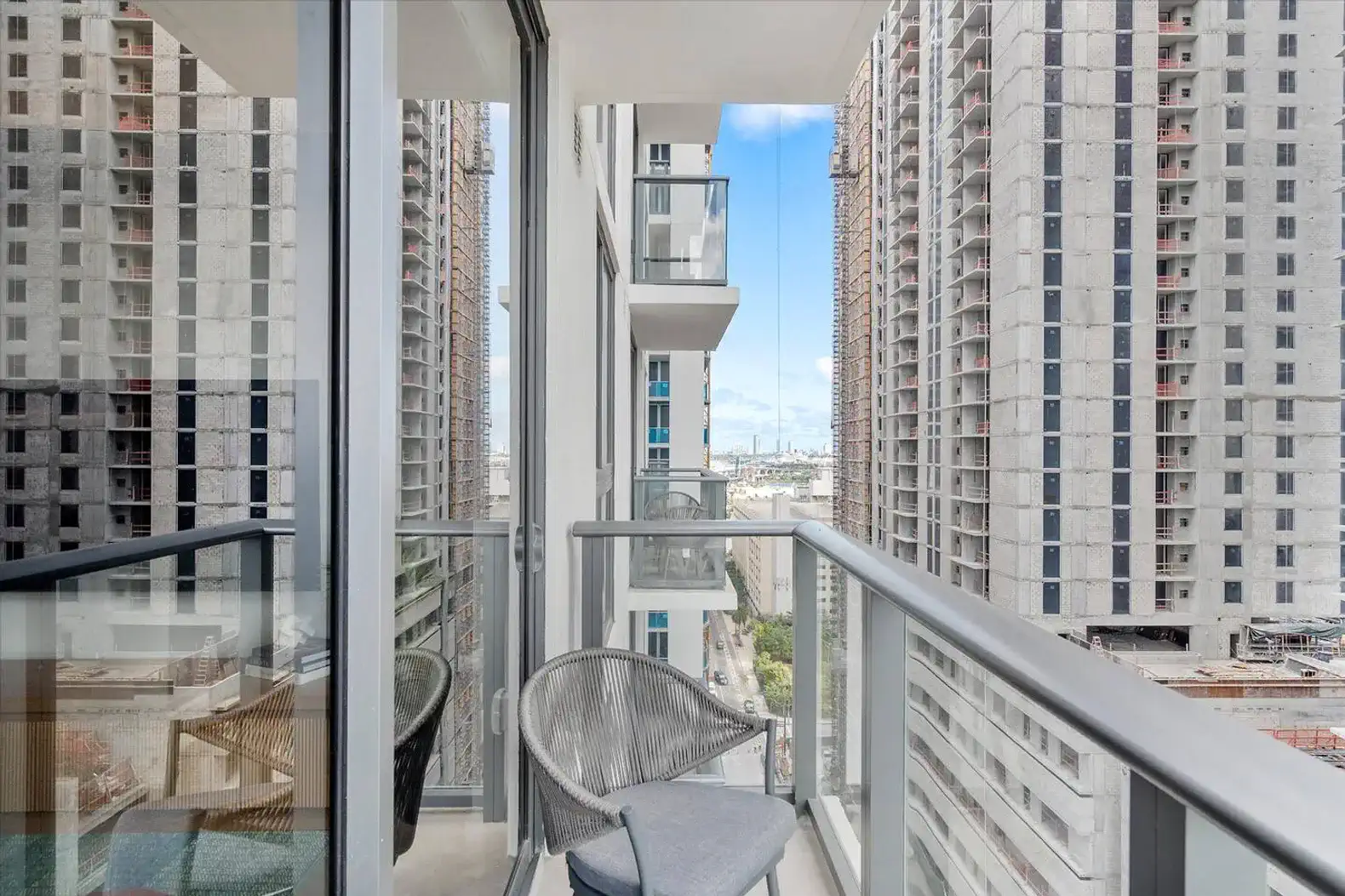 Balcony with a chair overlooking city views and nearby construction
