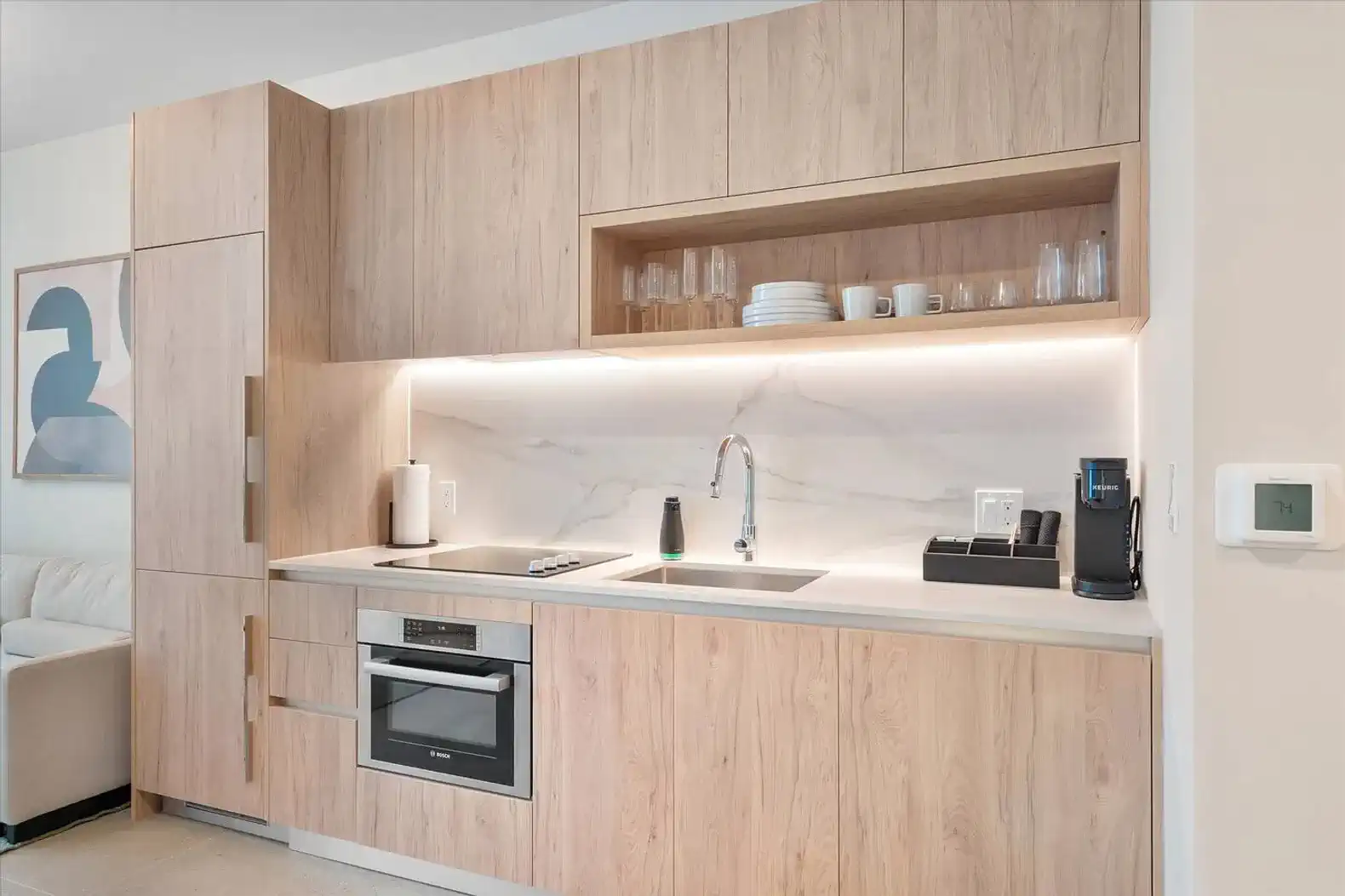 Modern kitchen with wood cabinetry, marble backsplash, and stainless steel appliances