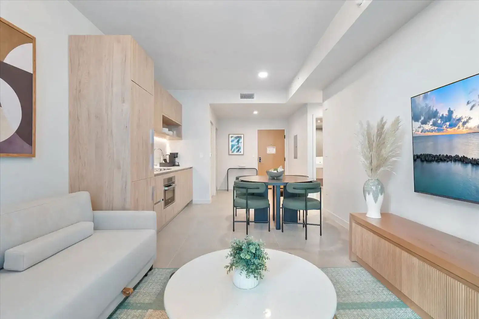 Modern living room with a sofa, dining table, and kitchen area featuring sleek cabinetry