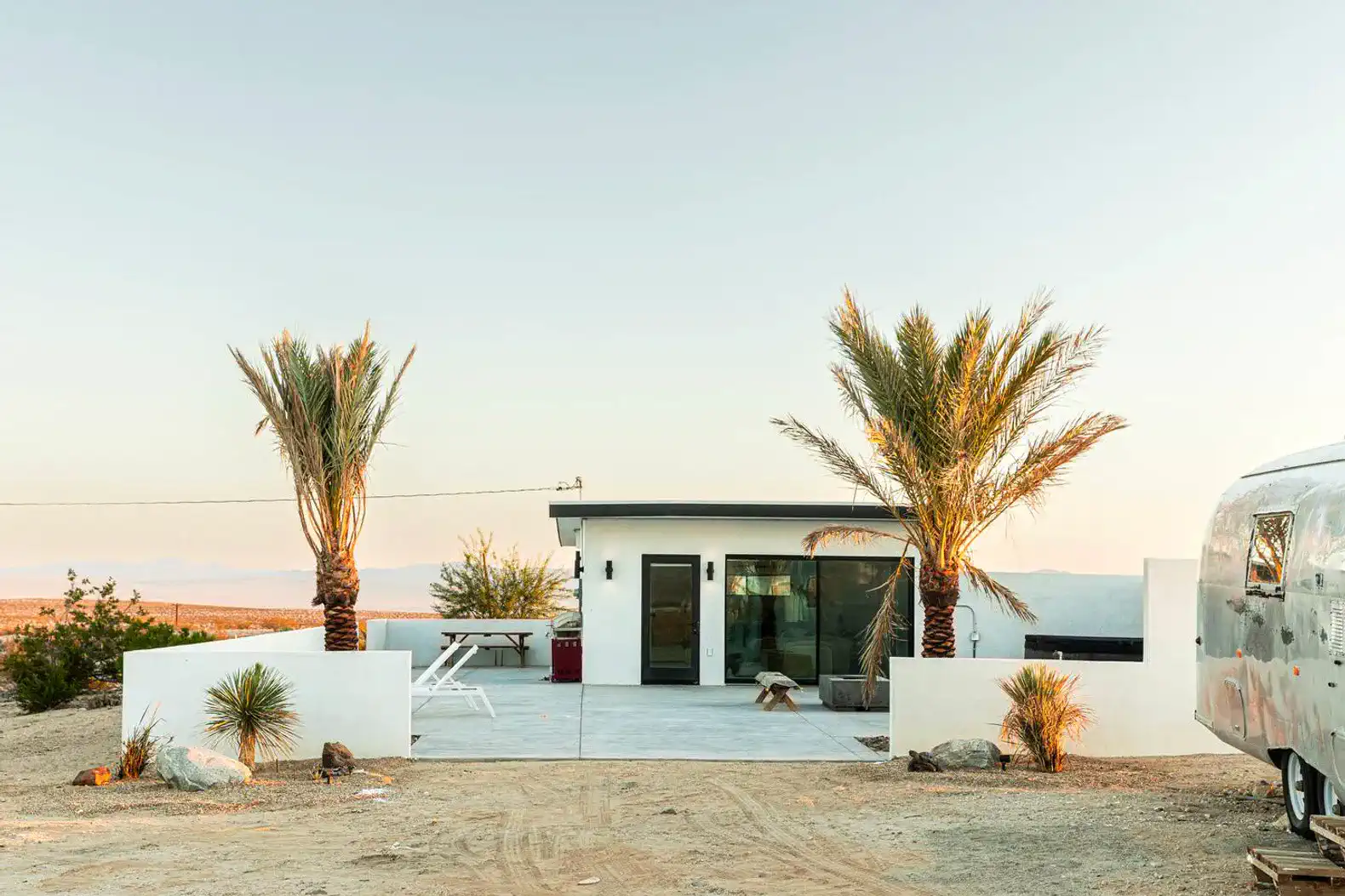 Modern desert home with palm trees and outdoor seating area