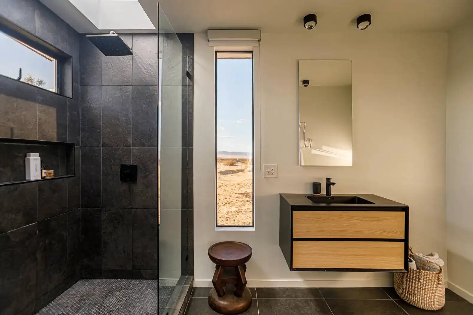 Modern bathroom with a walk-in shower, sleek vanity, and large window showcasing desert views