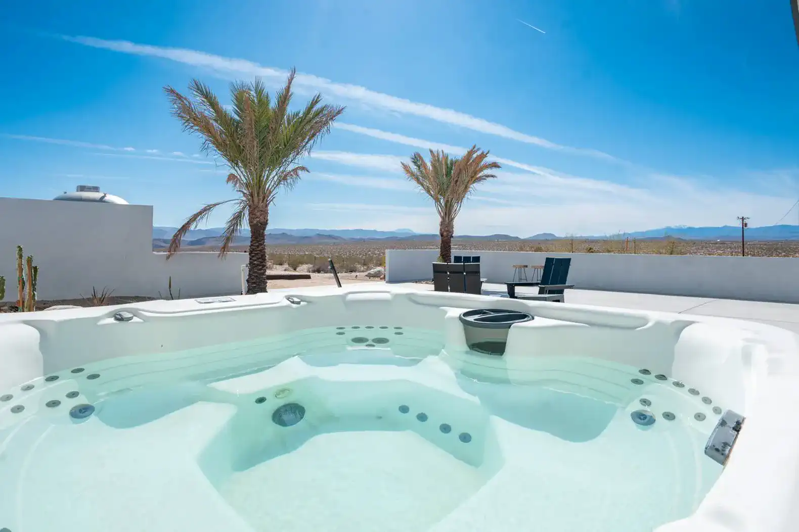 Hot tub with palm trees and desert view under a clear blue sky