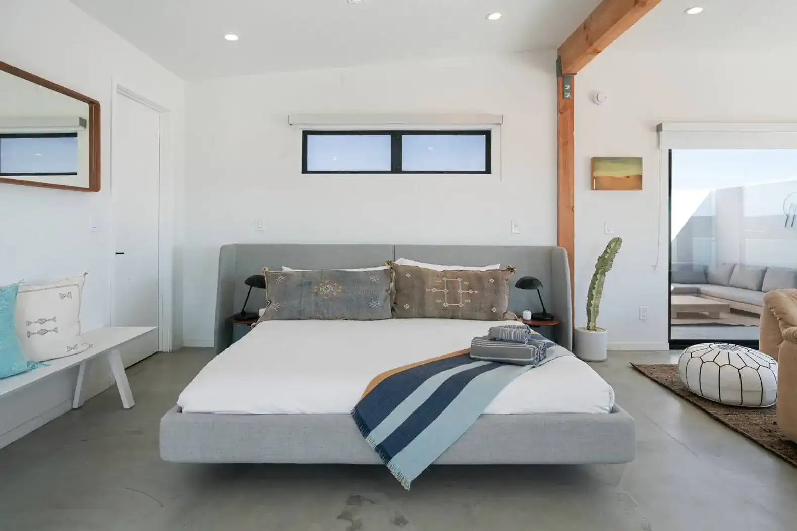 Stylish master bedroom with a modern bed, decorative pillows, and a view of the outdoor seating area