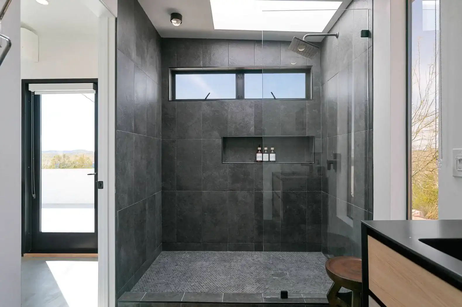 Spacious modern shower with dark tiles and natural light from skylights