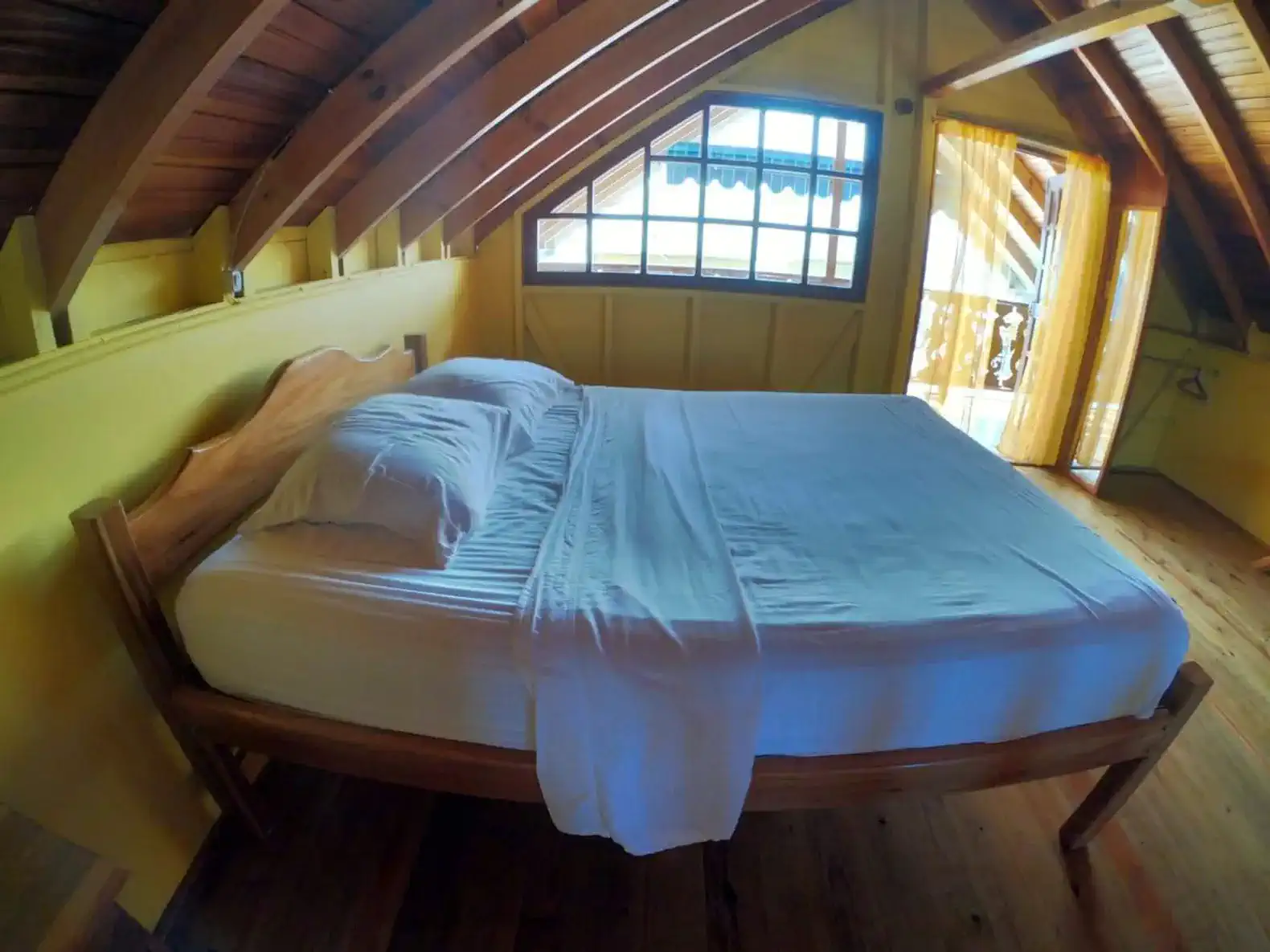 Cozy master bedroom with wooden beams and bright yellow walls
