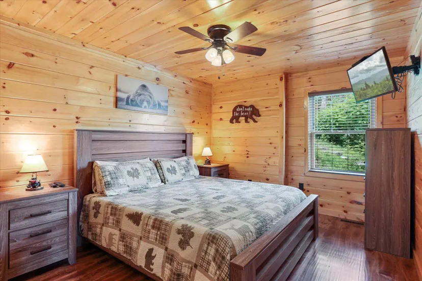 Cozy master bedroom with wooden walls, a king-size bed, and a TV