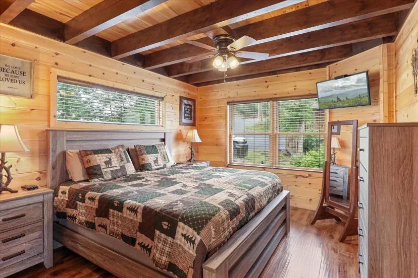 Gemütliches Hauptschlafzimmer mit Holzbalken, einem großen Bett und natürlichem Licht von den Fenstern