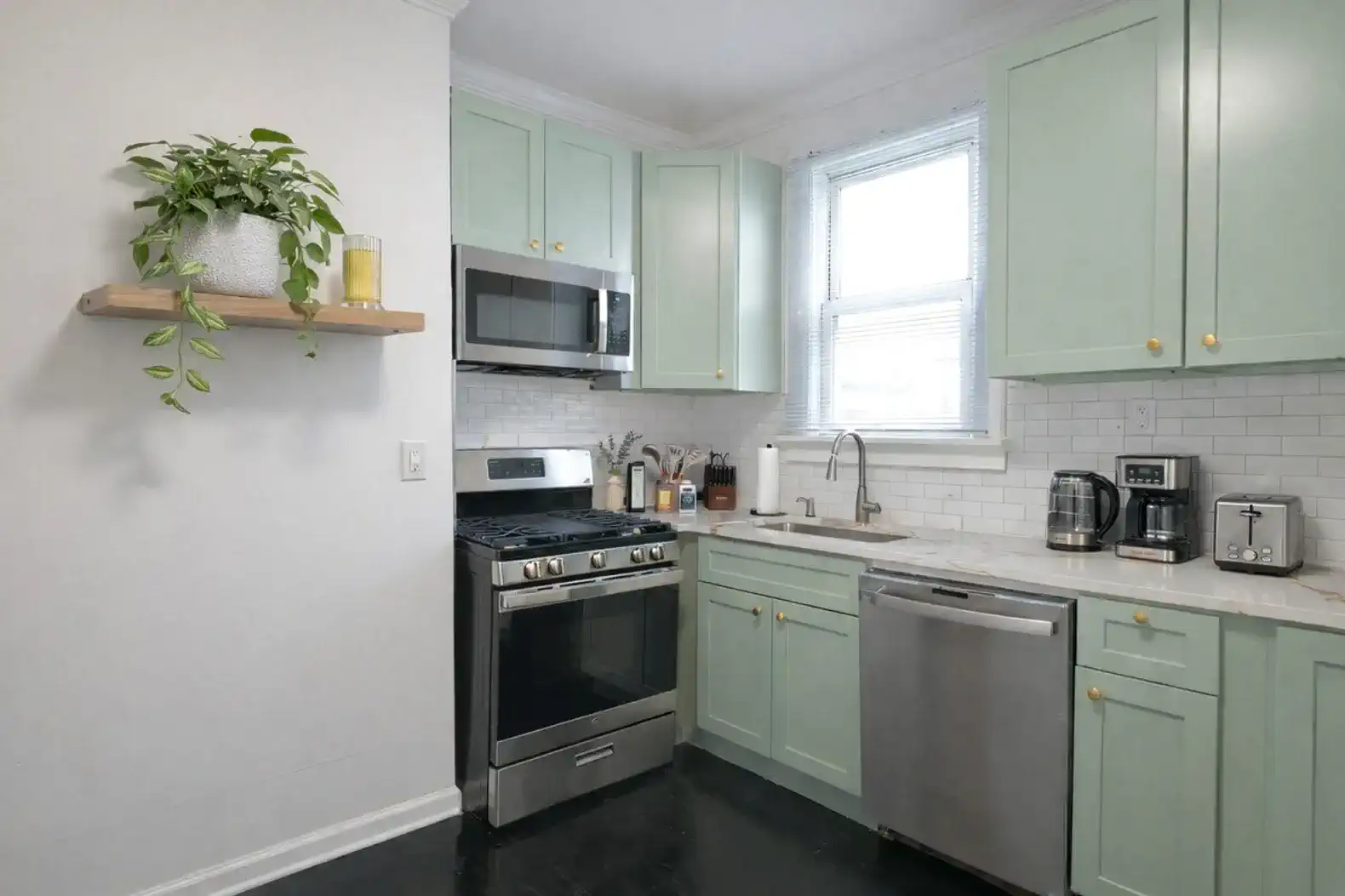 Cozy kitchen with mint green cabinets, stainless steel appliances, and a window for natural light