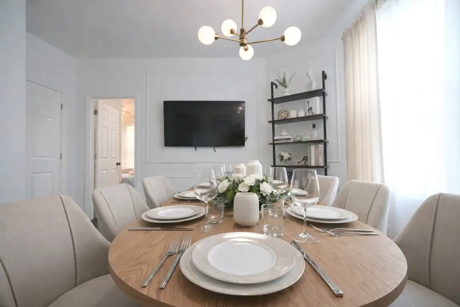 Elegant dining area with a round table set for dinner and modern lighting
