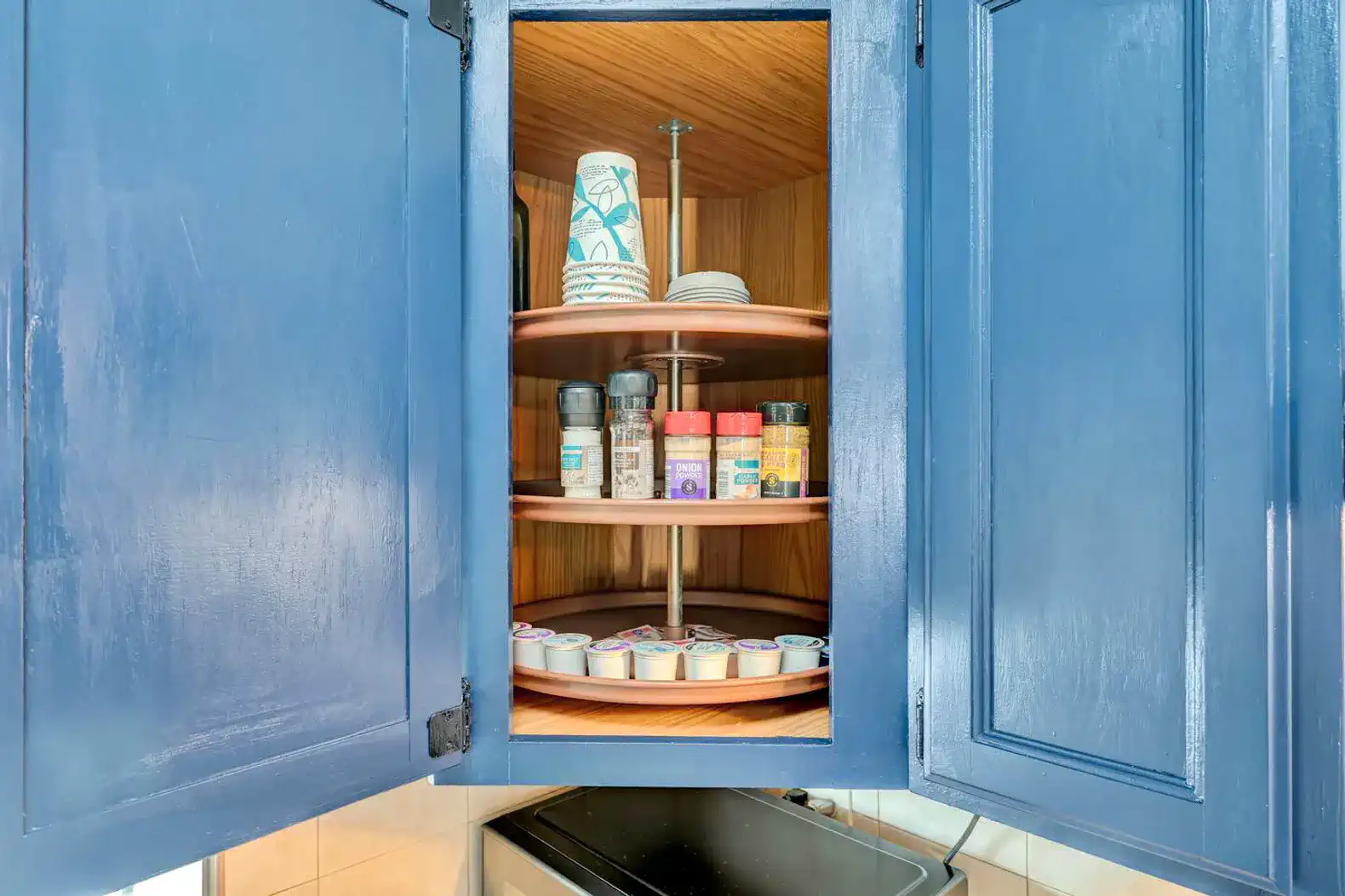 Spice rack with various containers and cups in a blue cabinet
