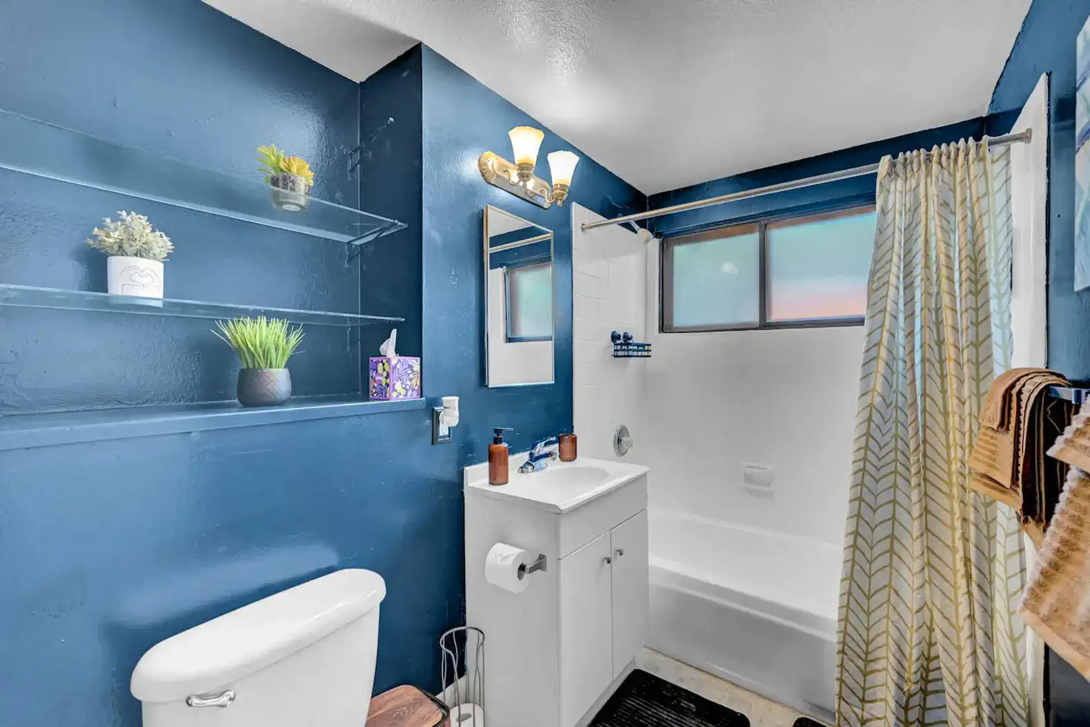 Modern bathroom with blue walls, shower tub combo, and stylish decor