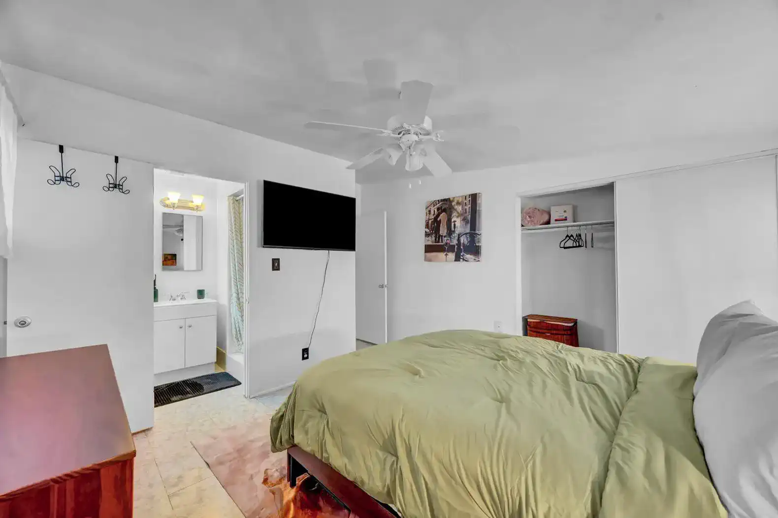 Cozy master bedroom with a green comforter, TV, and attached bathroom