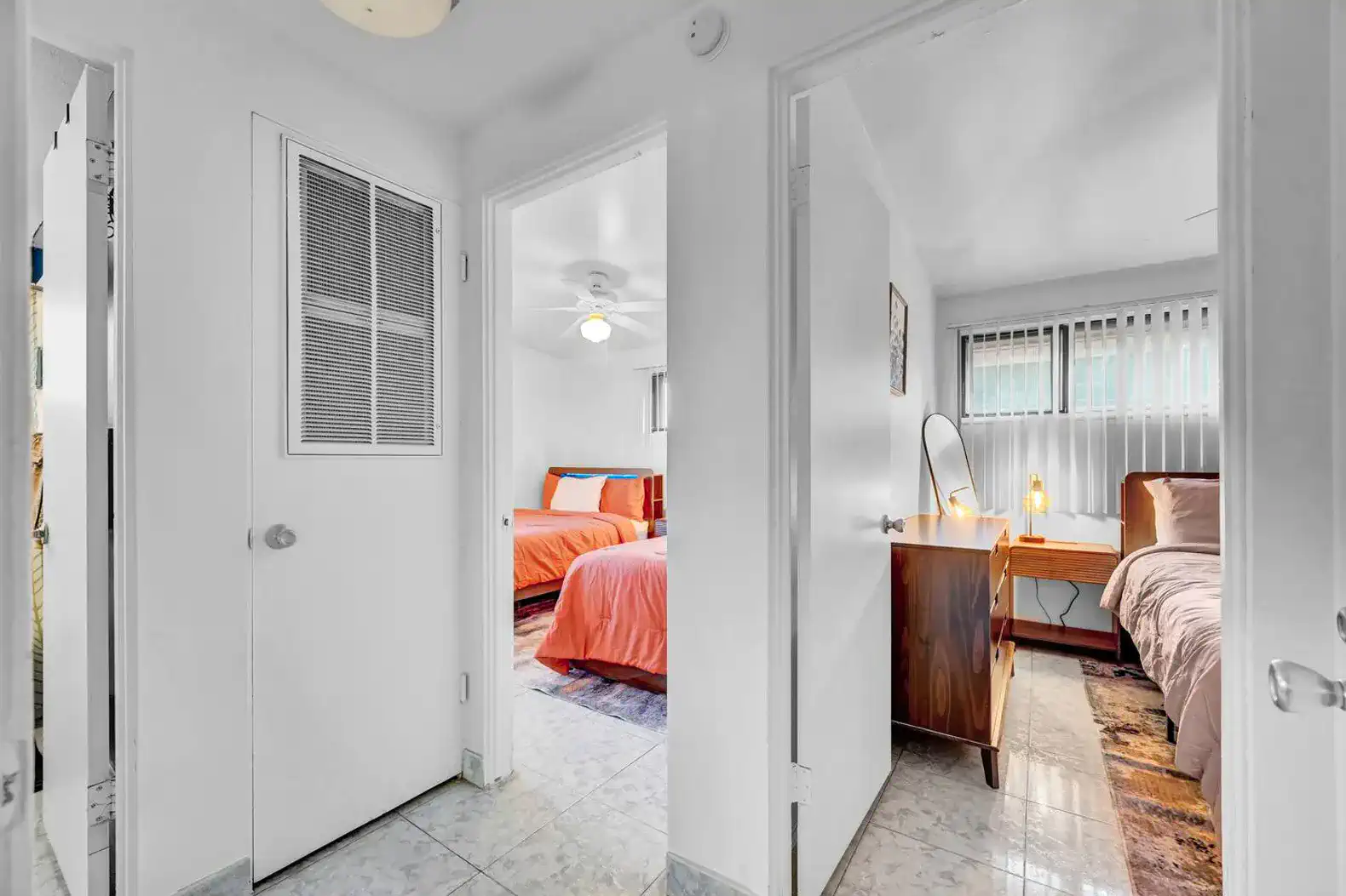 Bright hallway leading to two bedrooms with colorful bedding and natural light