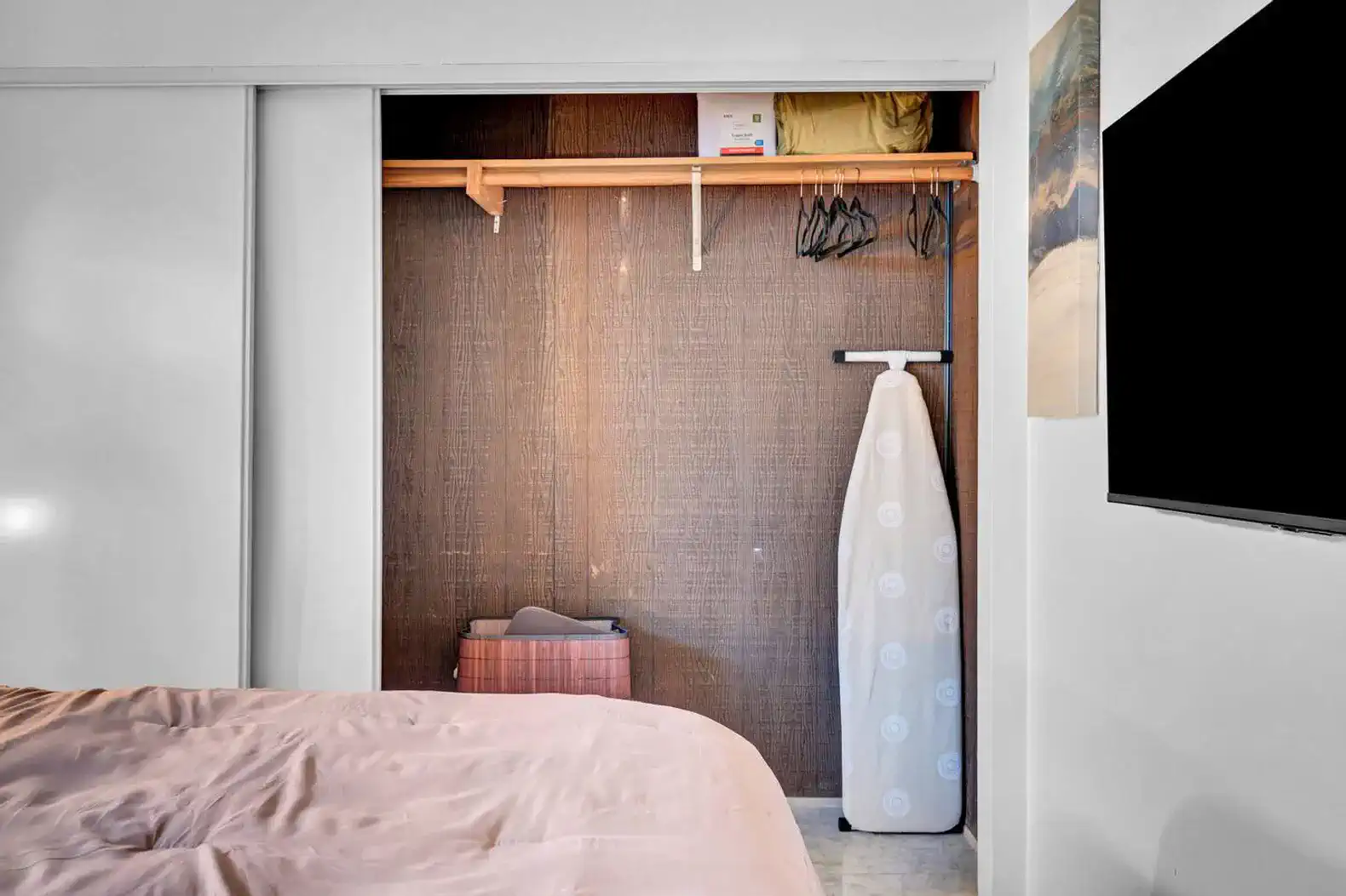 Cozy closet space with ironing board and storage bins