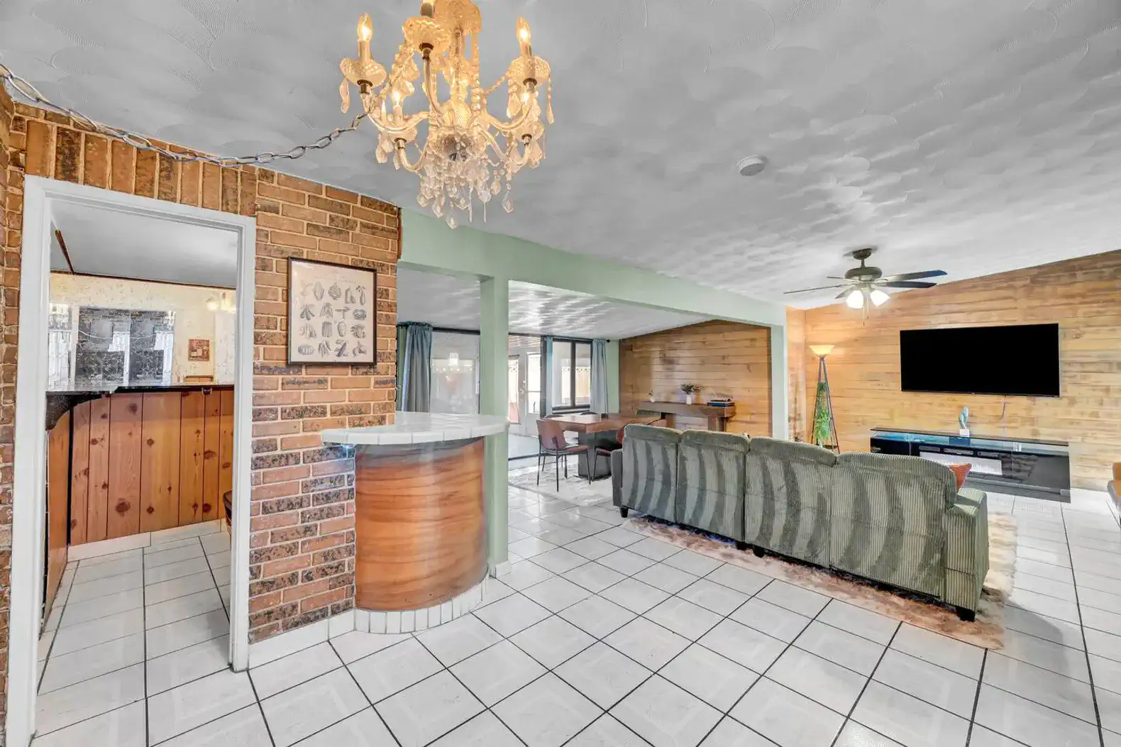 Spacious living area with a chandelier, brick accents, and a view of the dining area