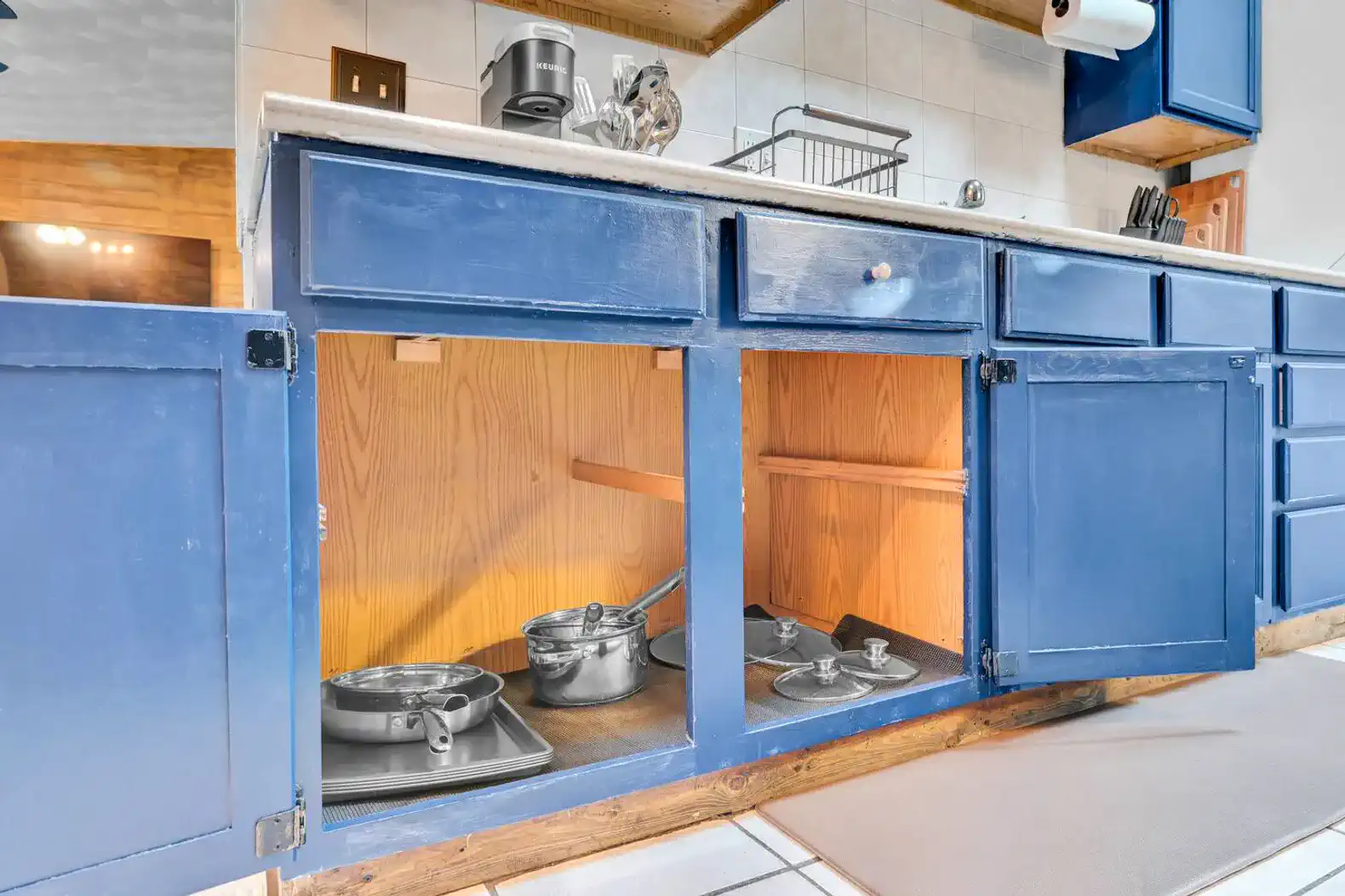 Blue kitchen cabinets with pots and pans stored underneath