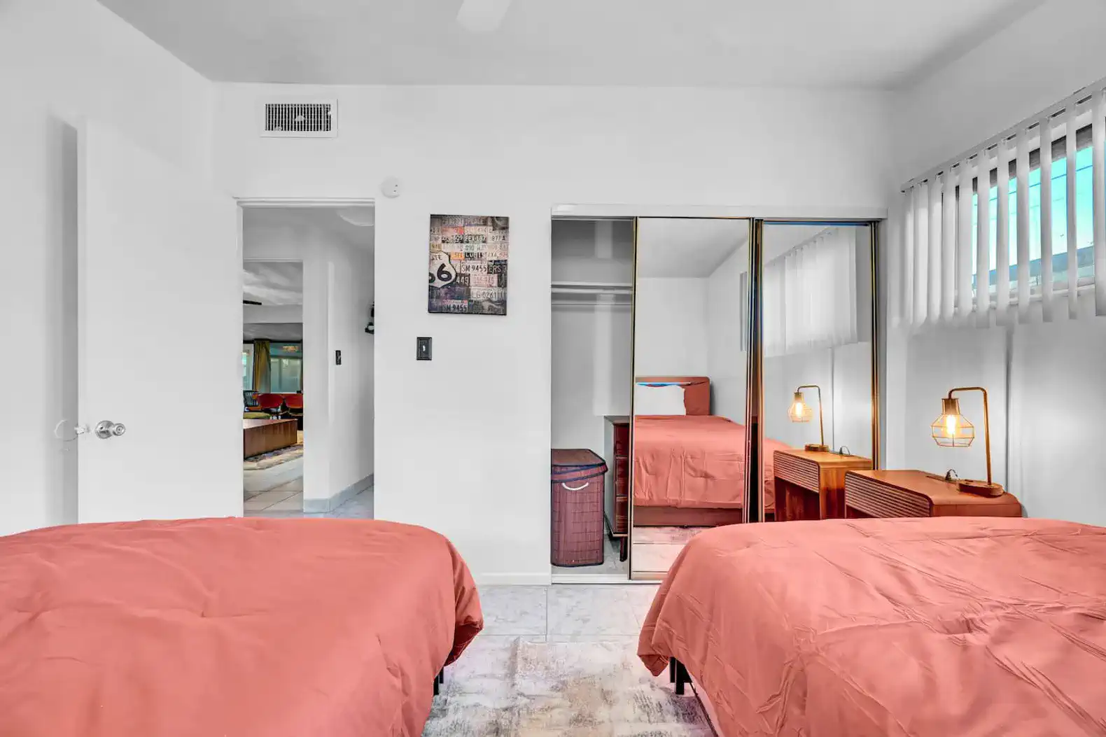 Cozy guest bedroom with two beds, mirrored closet, and warm lighting