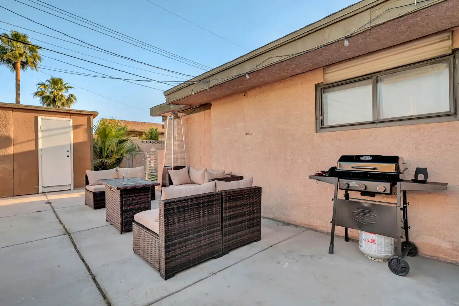 Outdoor seating area with a grill and palm trees nearby
