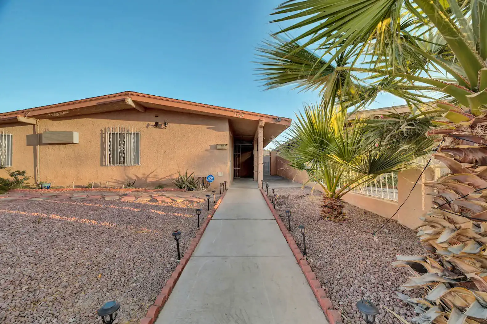 Pathway leading to the entrance with palm trees and desert landscaping