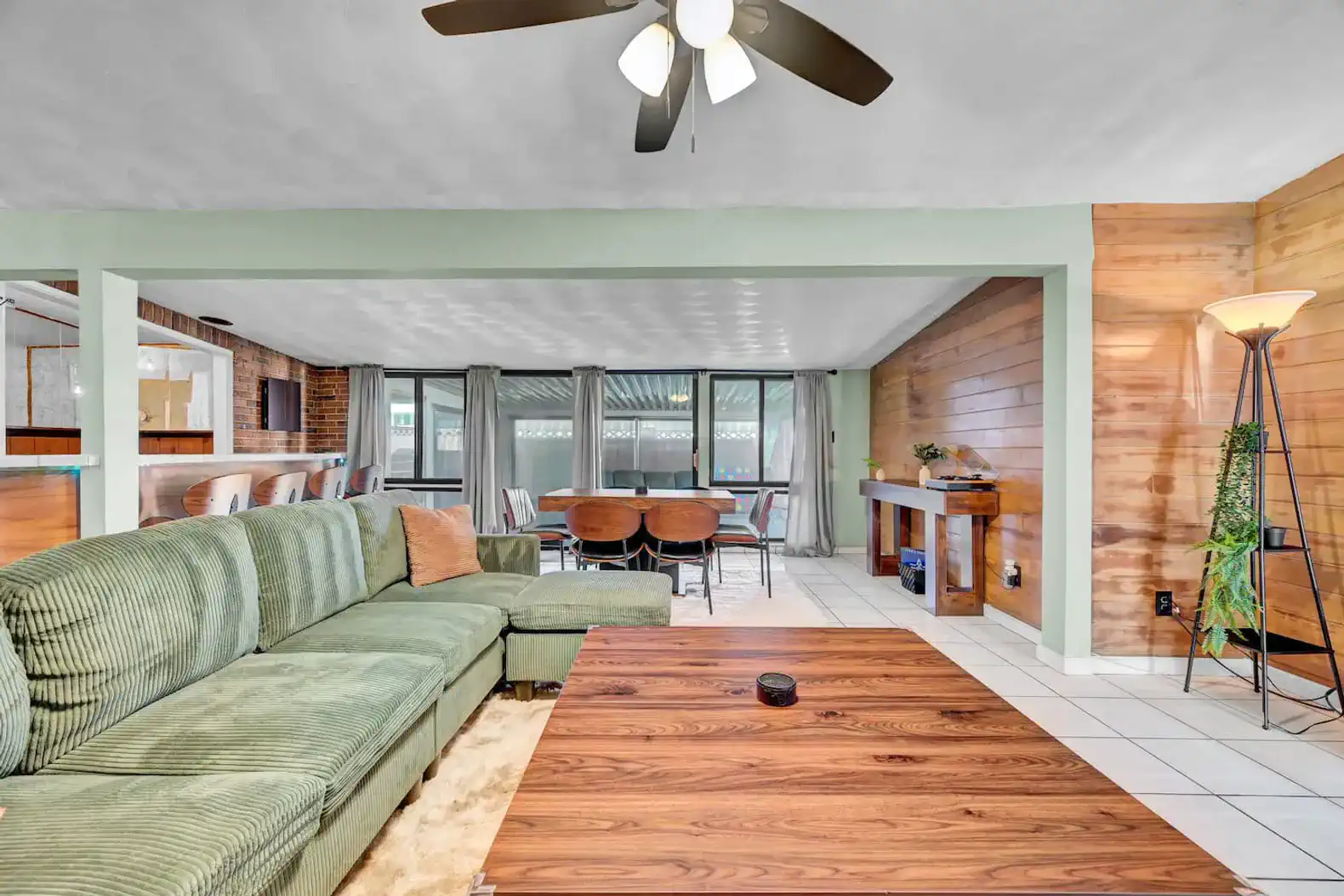 Spacious living area with green sectional sofa and dining table