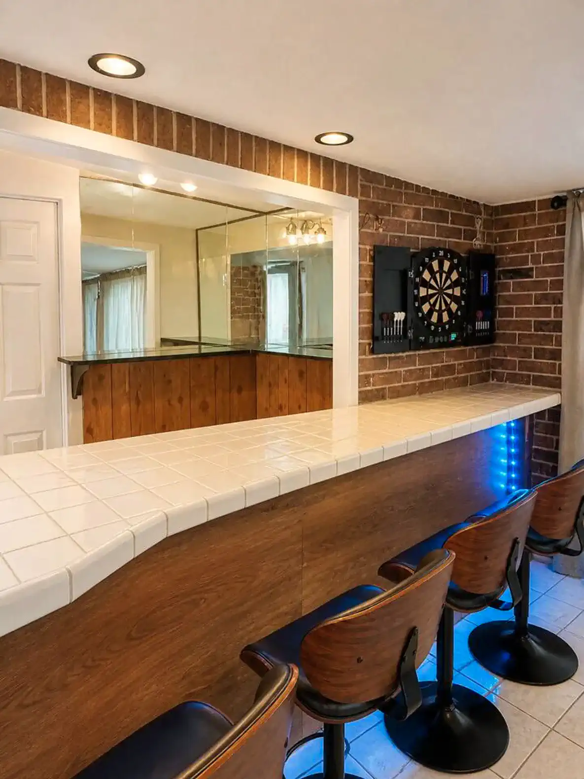 Stylish bar area with seating and dartboard against a brick wall