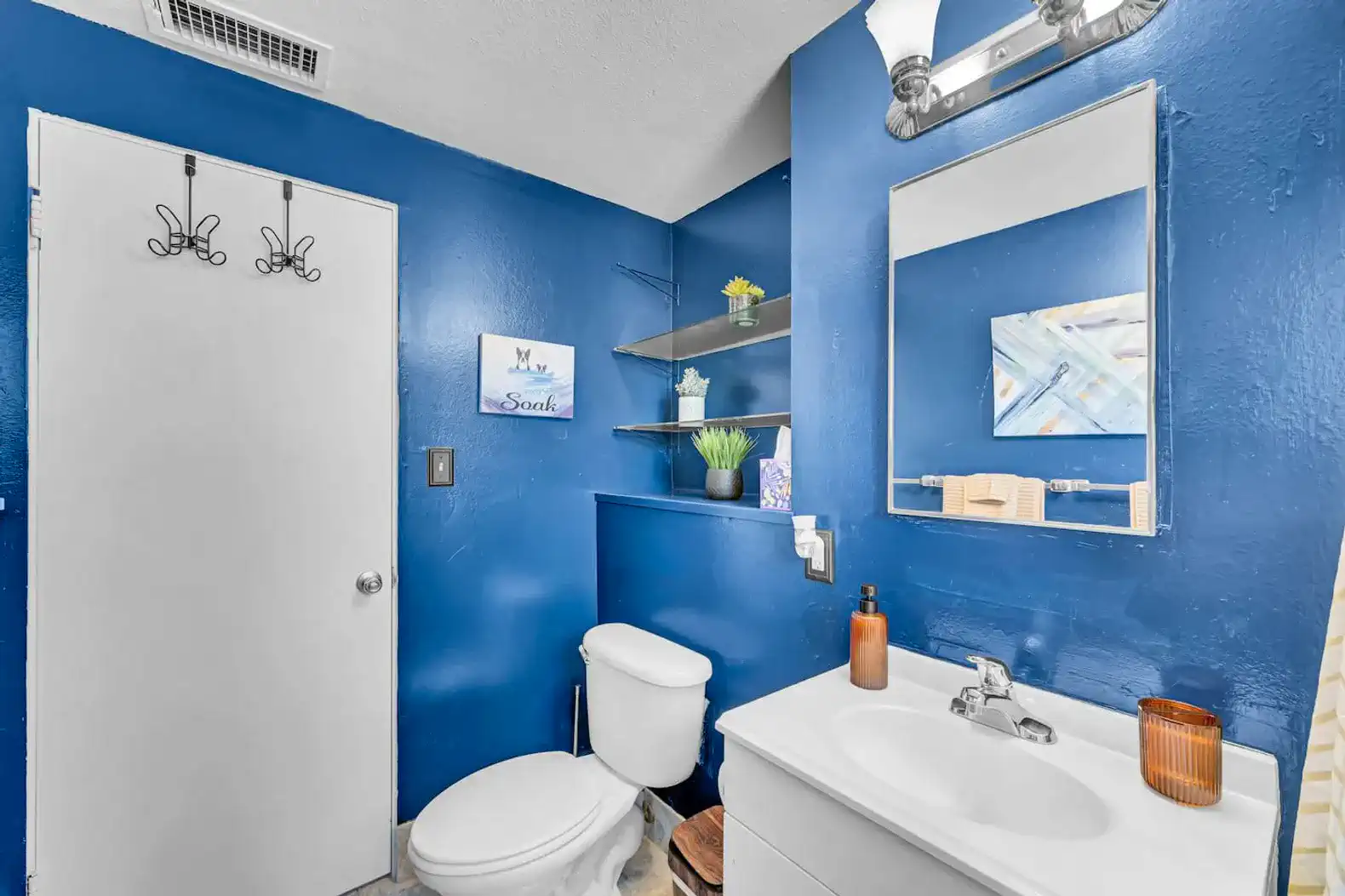 Bright blue bathroom with modern fixtures and decorative shelves