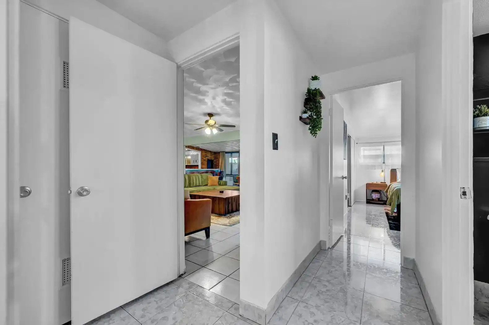 Bright hallway leading to living room and bedrooms with tiled flooring