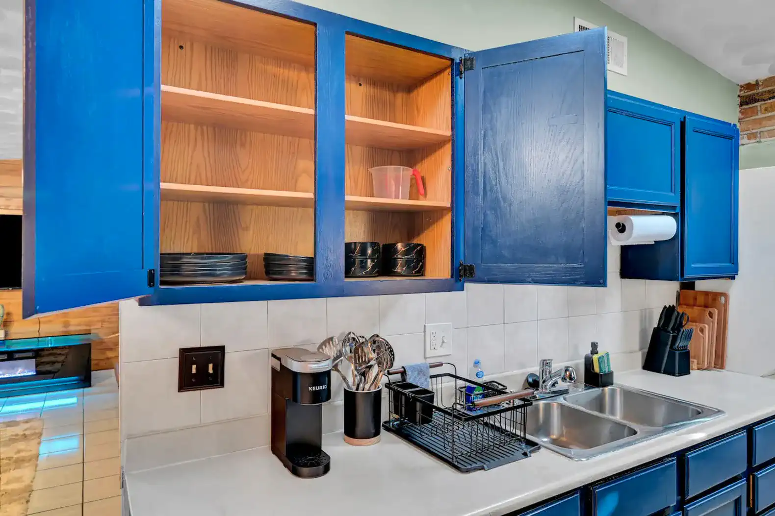 Bright kitchen with blue cabinets and open shelves displaying dishes