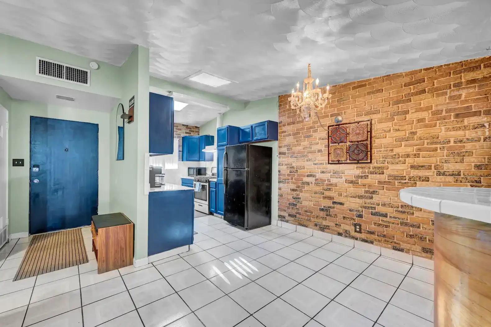Bright kitchen with blue cabinets, brick wall, and modern appliances