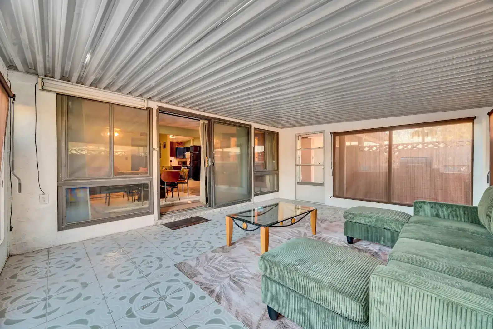 Spacious covered patio with green furniture and glass table