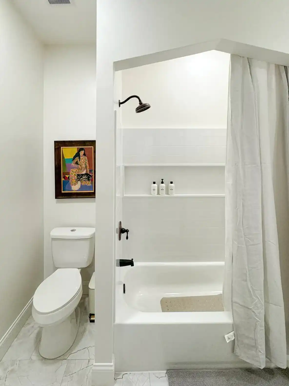 Bright bathroom featuring a shower-tub combo with modern fixtures and decorative art