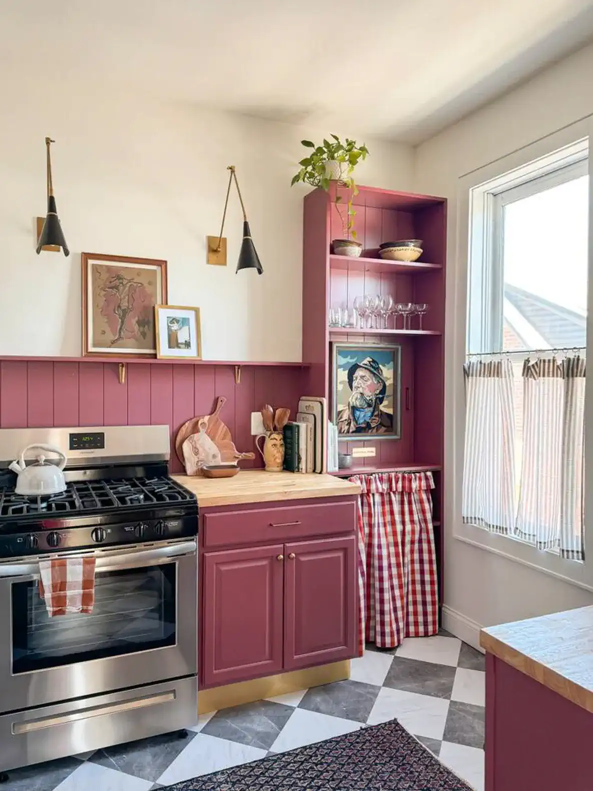 Charming kitchen with pink cabinets, stainless steel appliances, and a window with checkered curtains