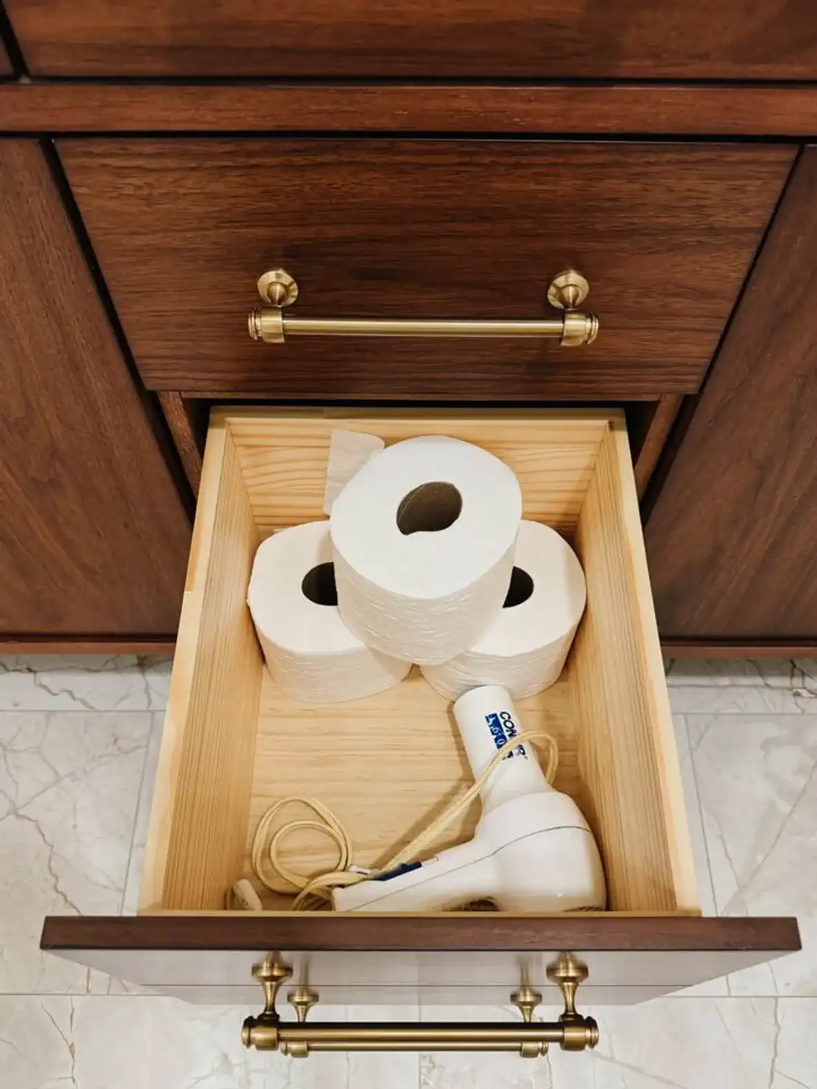 Wooden drawer containing toilet paper rolls and a hair dryer
