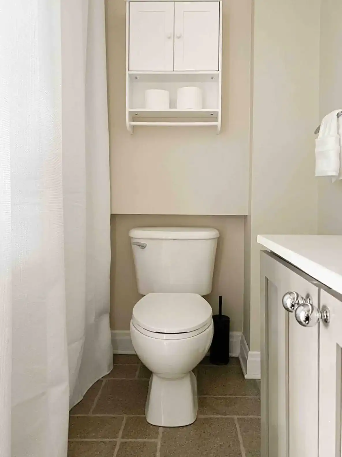 Bright and clean bathroom featuring a toilet and storage shelf