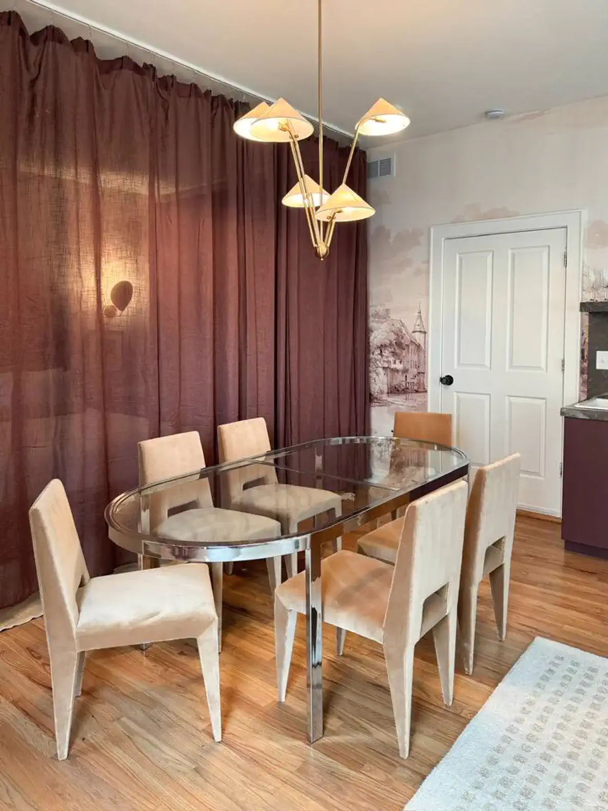 Elegant dining area with a glass table and stylish chairs under a modern chandelier