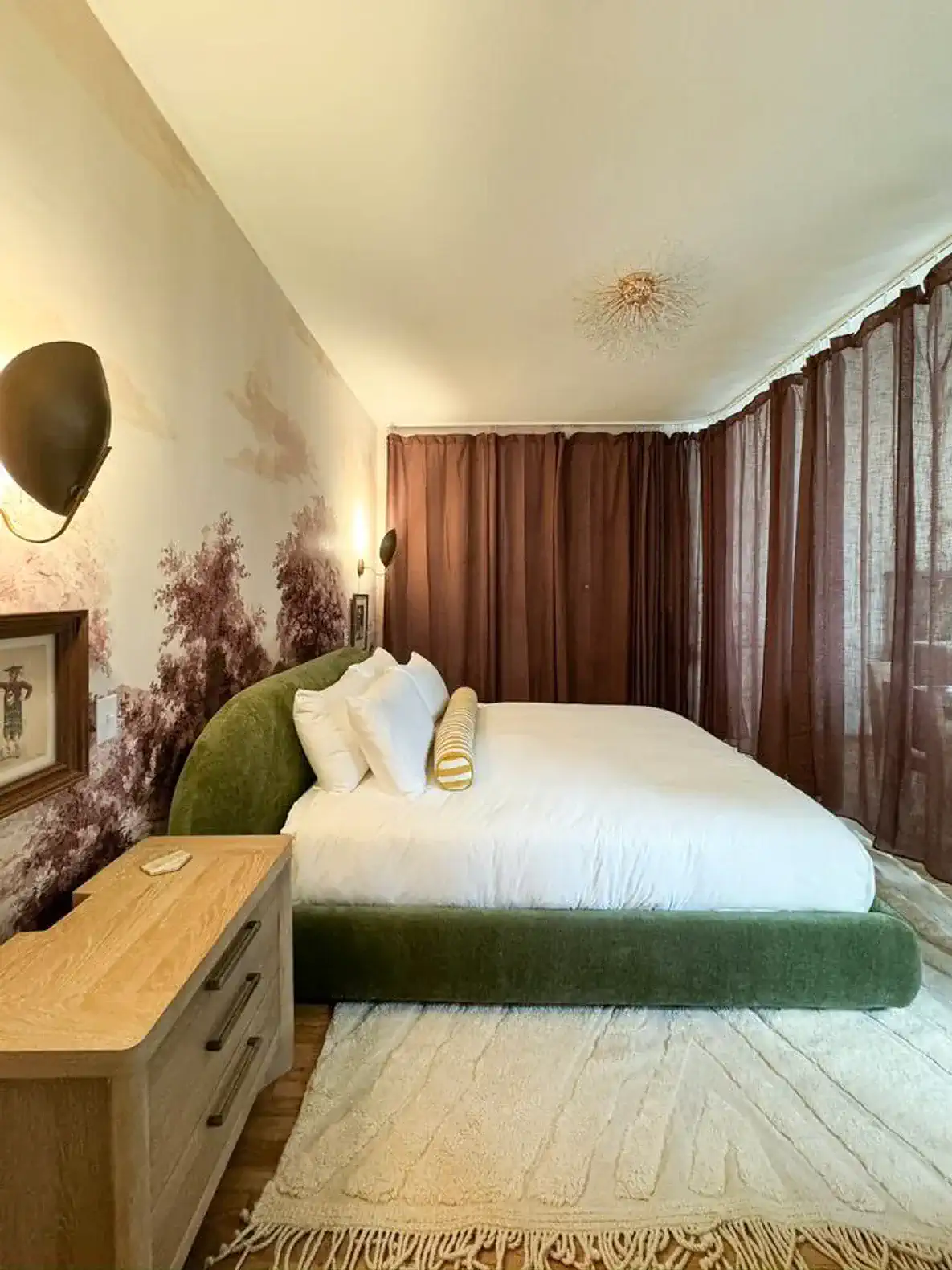 Cozy master bedroom with green upholstered bed and warm lighting