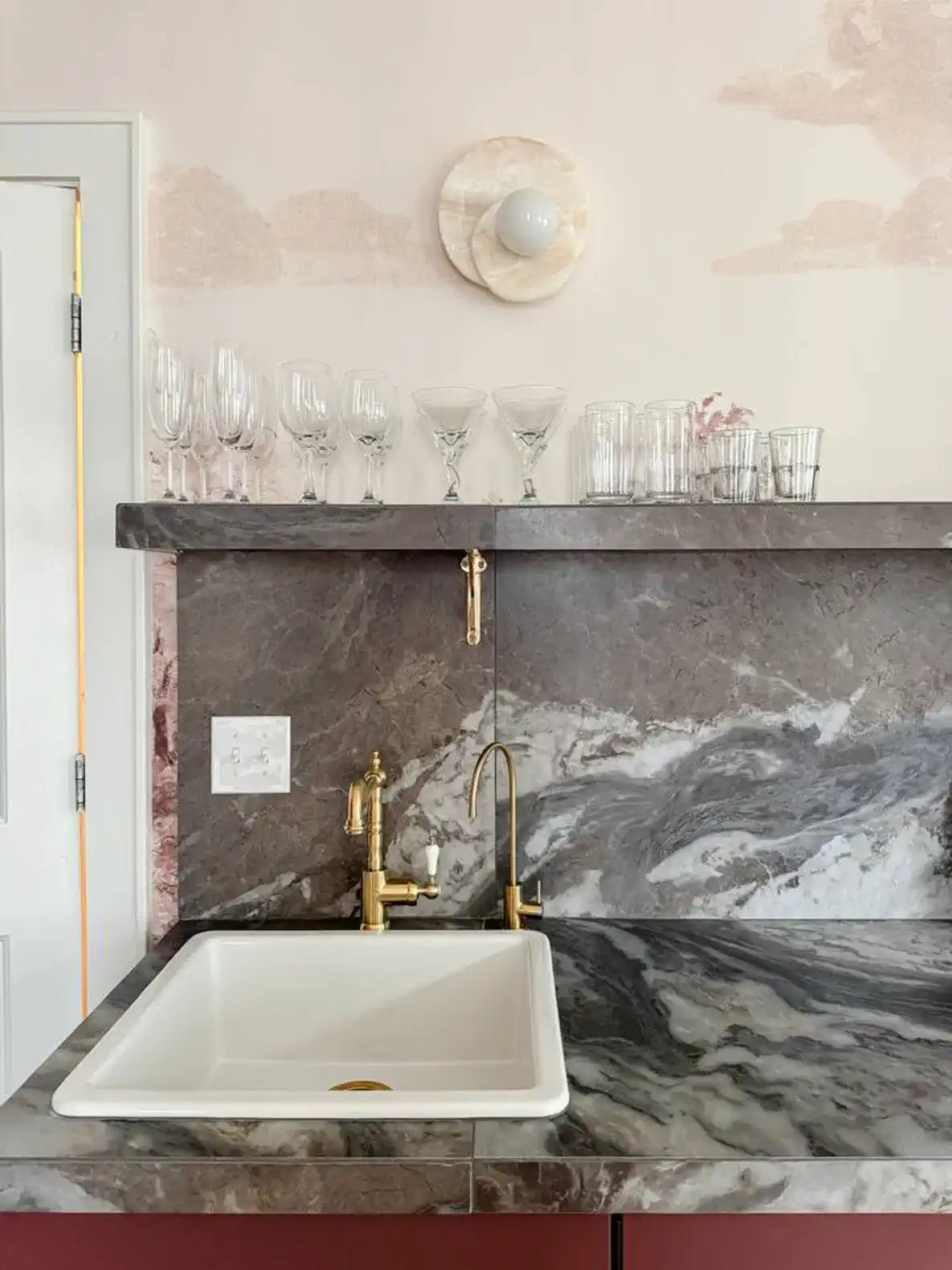 Stylish kitchen sink with marble countertop and glassware above