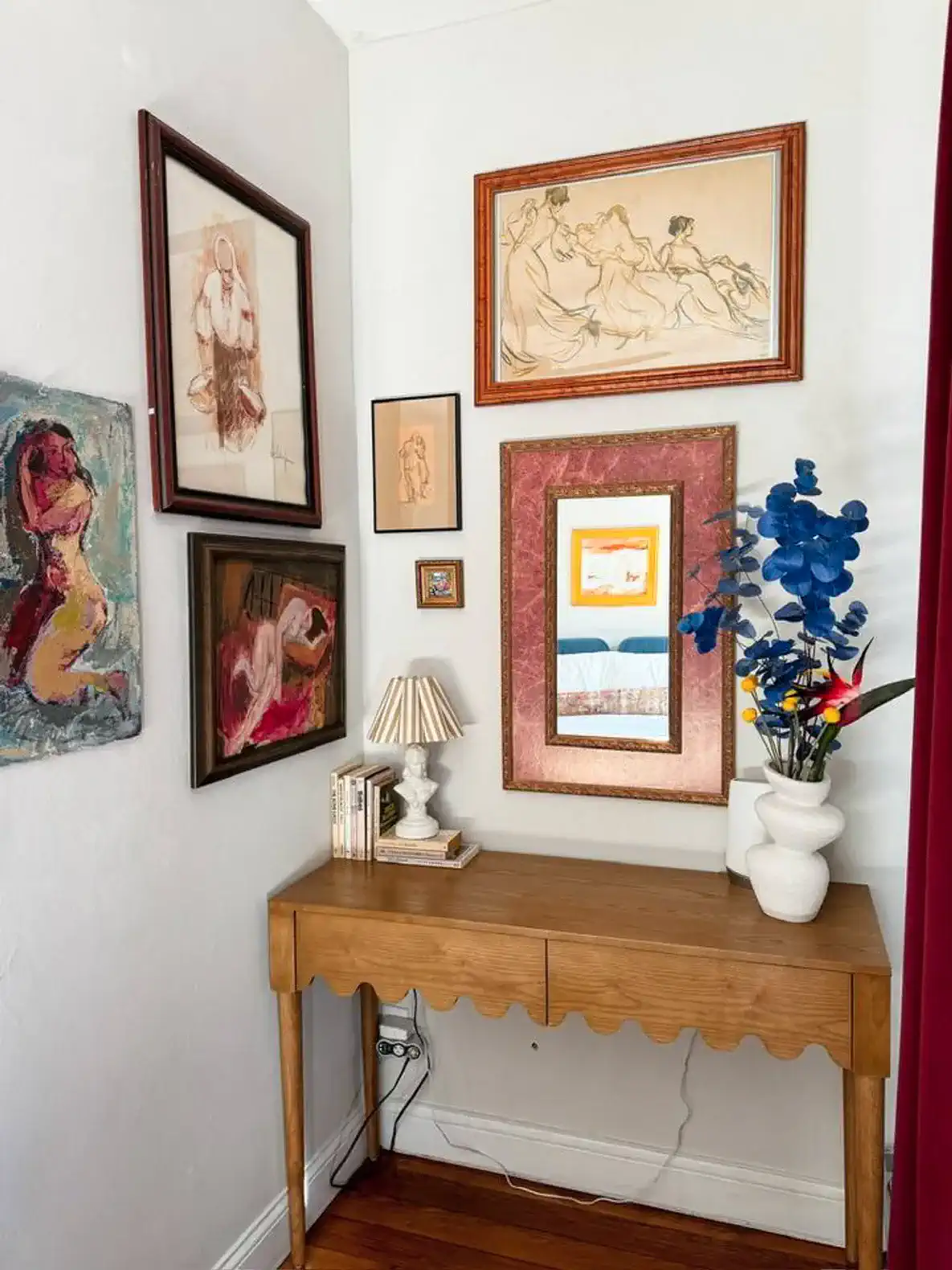 Artistic corner featuring framed artwork and a decorative table with a lamp and flowers